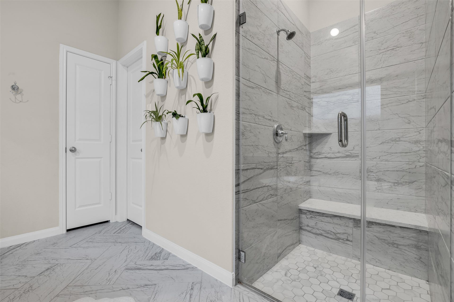 A walk-in glass shower with marble-look tile and a built-in bench brings a spa-style feel to everyday routines.