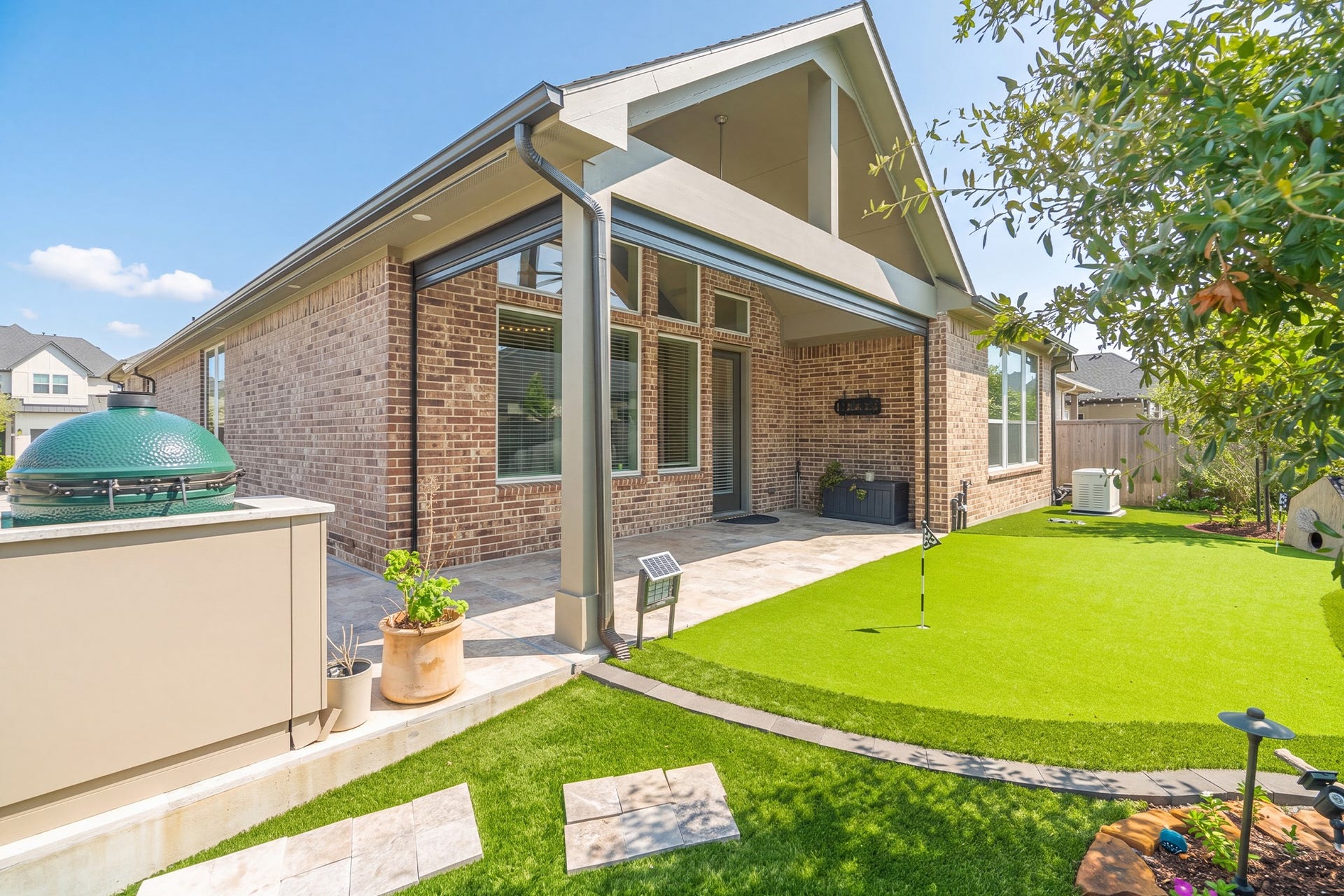The backyard brings it all together: the pool, a deep covered patio, space set up for outdoor cooking and a neatly kept lawn, all enclosed by fencing for privacy.