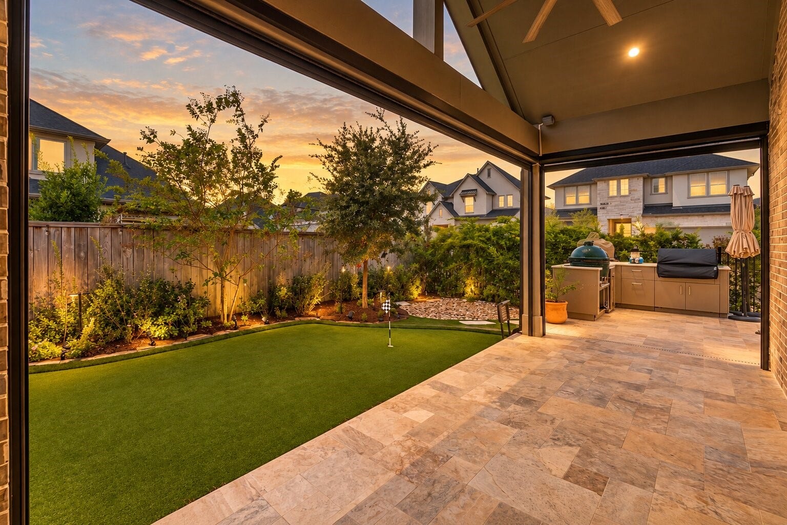 Evening on the covered back patio, where recessed lighting and a tiled floor open onto a level, fenced lawn - an easy spot for morning coffee or for entertaining friends after sunset.