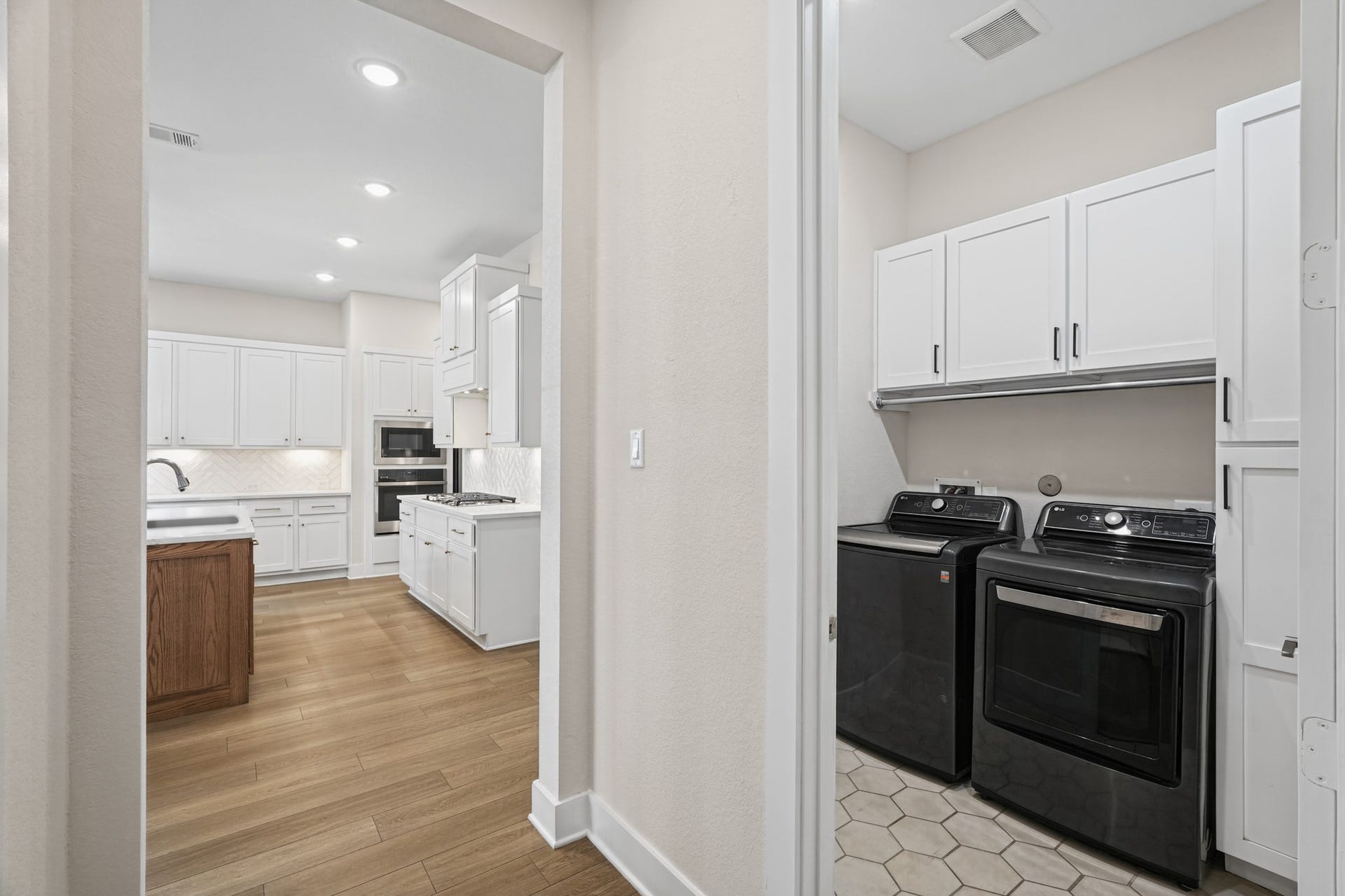 A gas range and additional cabinetry line the service side of the kitchen, with a pass-through to the main living area and quick access to the laundry room and garage entry.