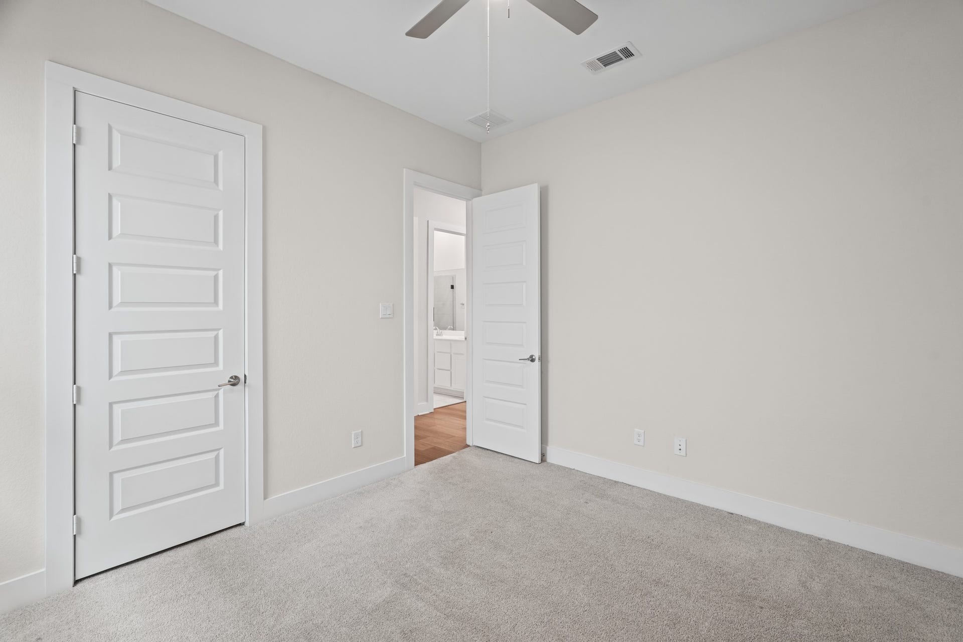 Hallway connecting the secondary bedrooms and bath, with wide doorways, linen storage and the same bright, neutral palette carried consistently throughout the home.