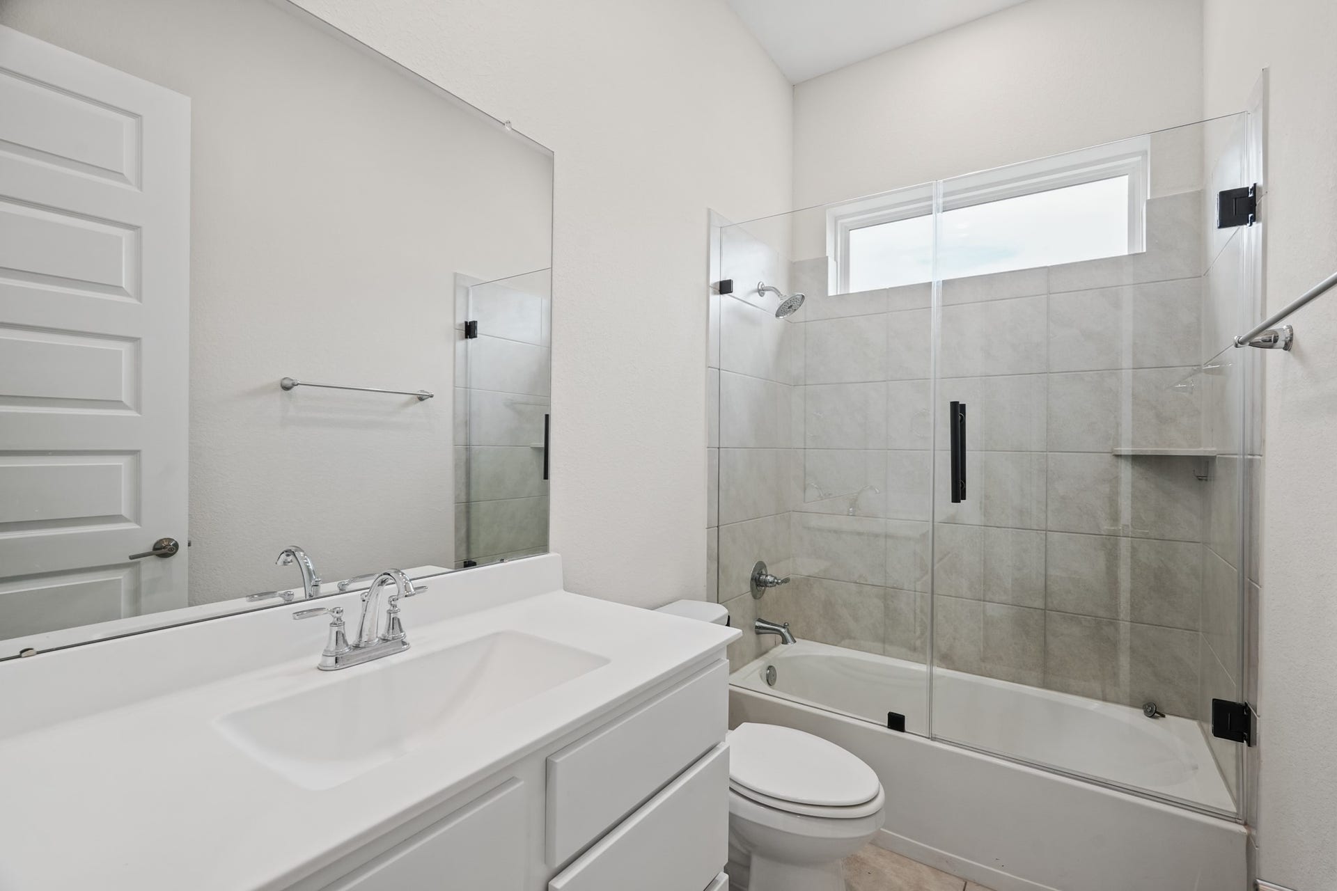 Full bath with a single vanity, a framed mirror and a glass-enclosed shower finished in clean, light tile - bright, low-maintenance and practical for everyday use.