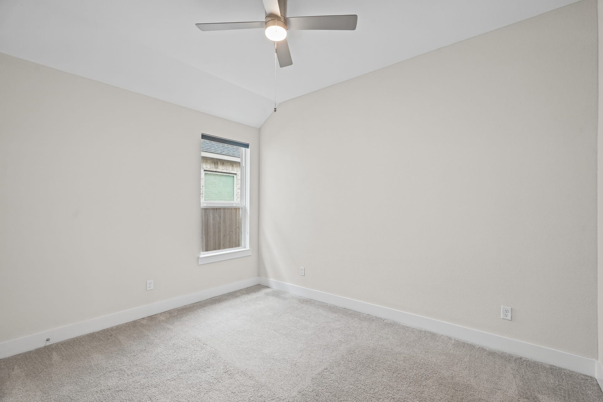 Another secondary bedroom with soft carpet, a ceiling fan and a window bringing in afternoon light - an easy flex space for a guest room, nursery or home gym setup.