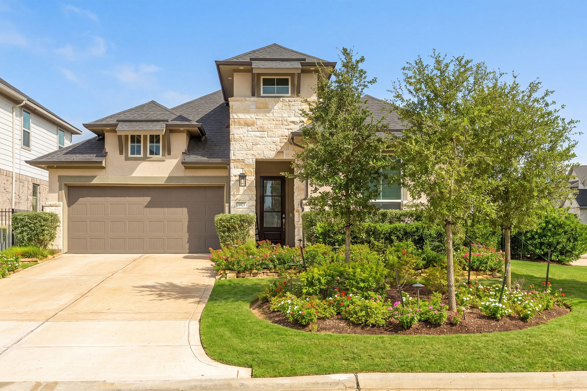 Angled view of the front elevation highlighting the covered entry, layered gable rooflines and mature foundation planting that give the home real curb appeal from the street.