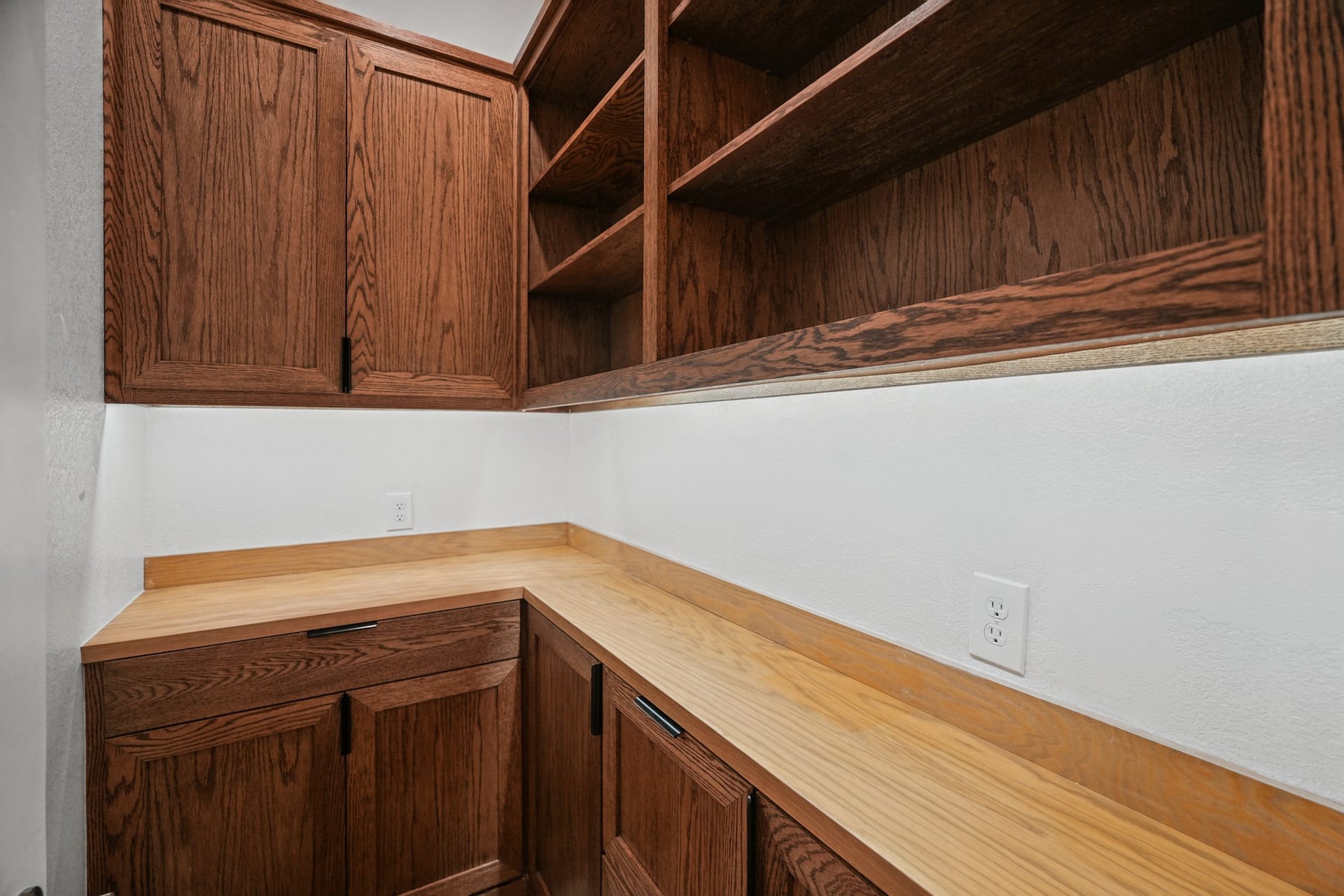 Dedicated laundry room includes wood cabinetry, a folding counter and open shelving, with space for a full-size washer and dryer plus extra household storage above.