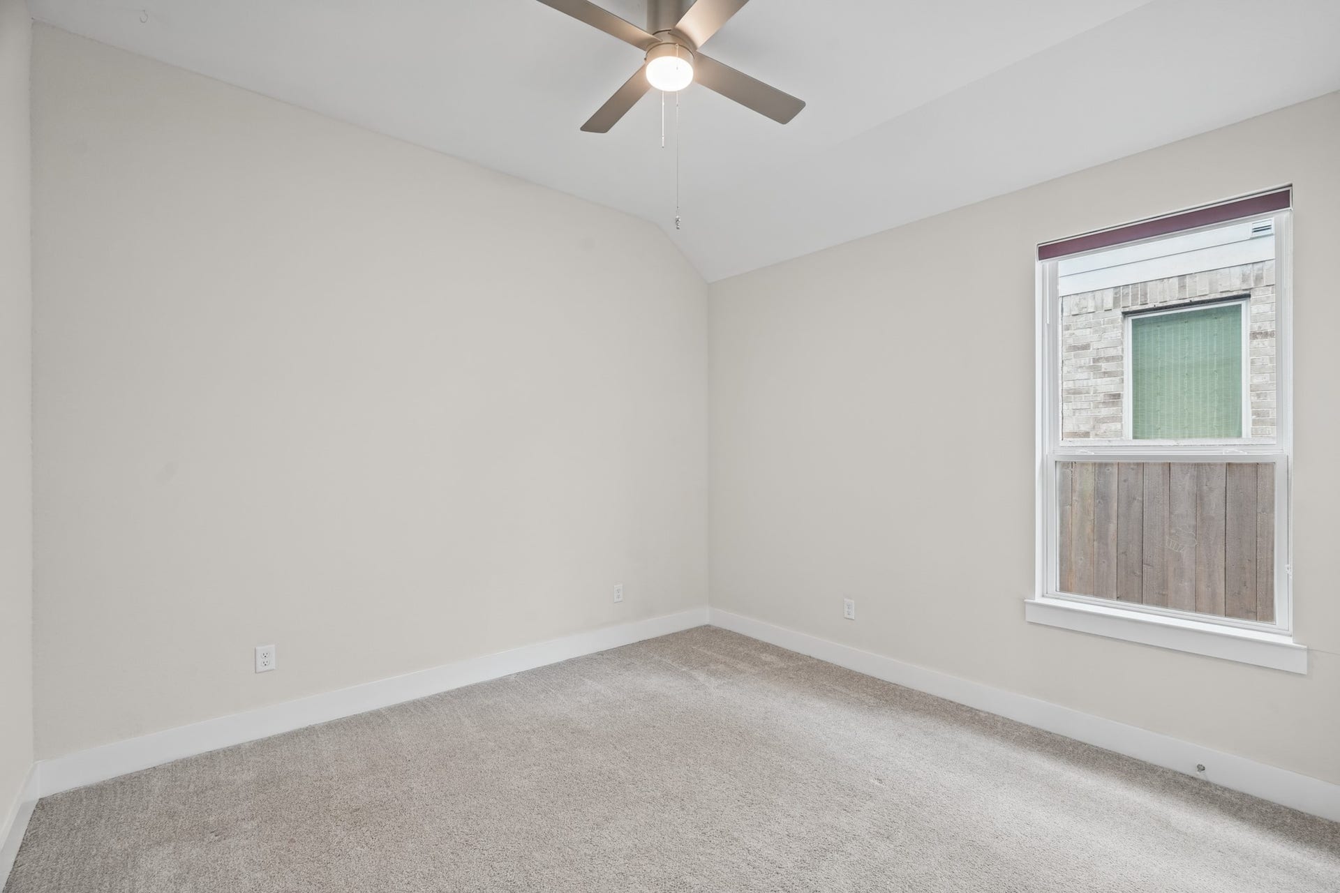 Secondary bedroom with soft carpet, a ceiling fan and a window overlooking the yard, sized comfortably for a queen bed, nightstands and a dresser with room left over.