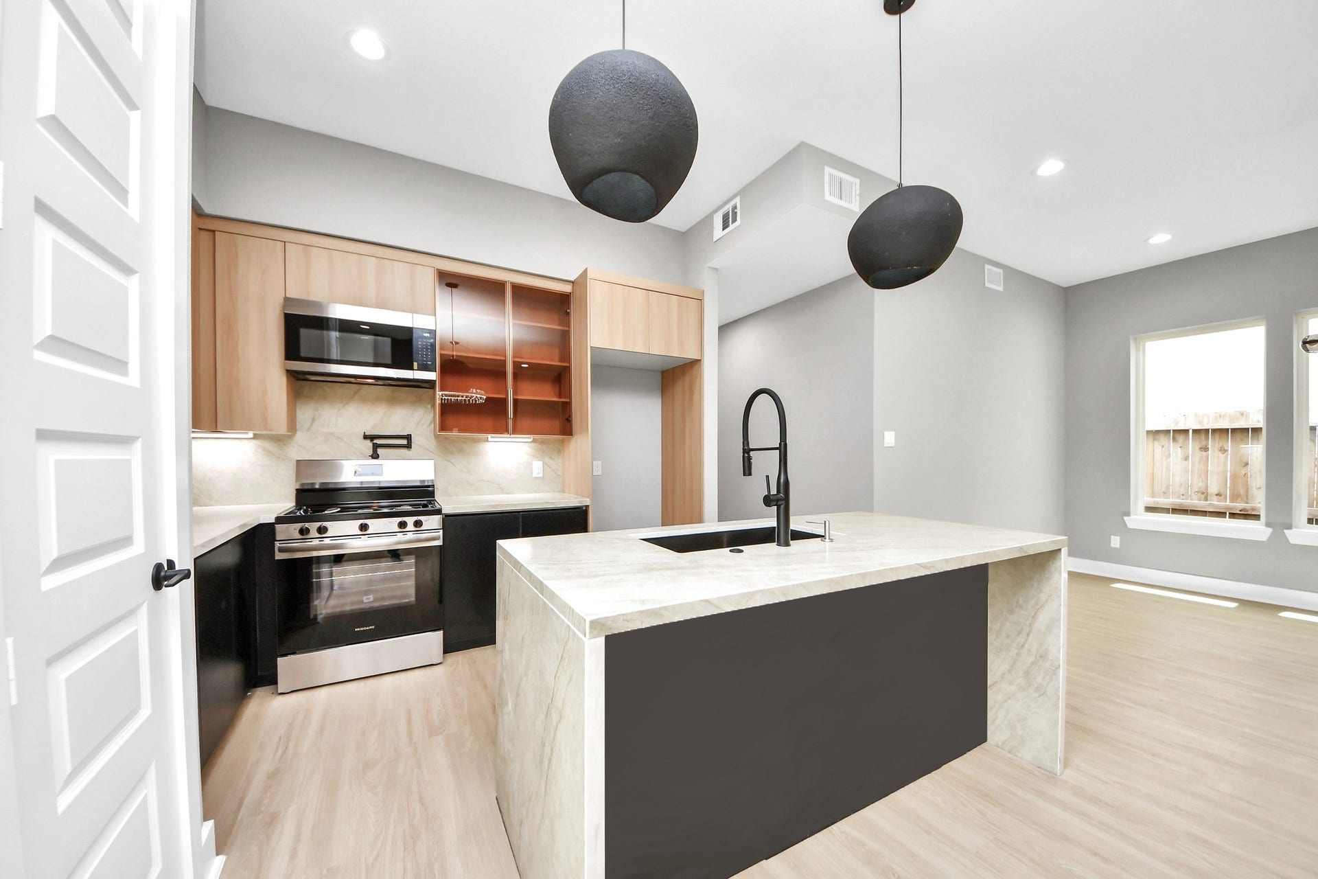 Warm cabinetry, a substantial island, stone surfaces and modern black fixtures create a kitchen with real presence.