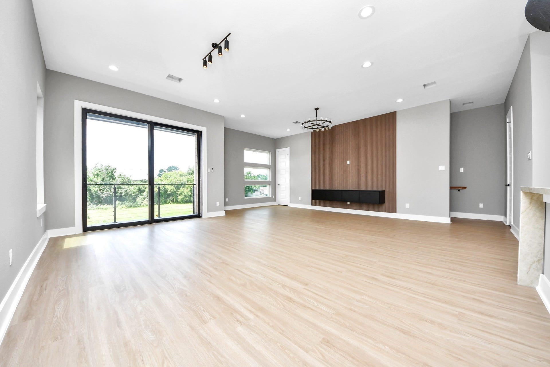 The actual vacant view reveals the generous scale, designer lighting, modern feature wall and abundant natural light.