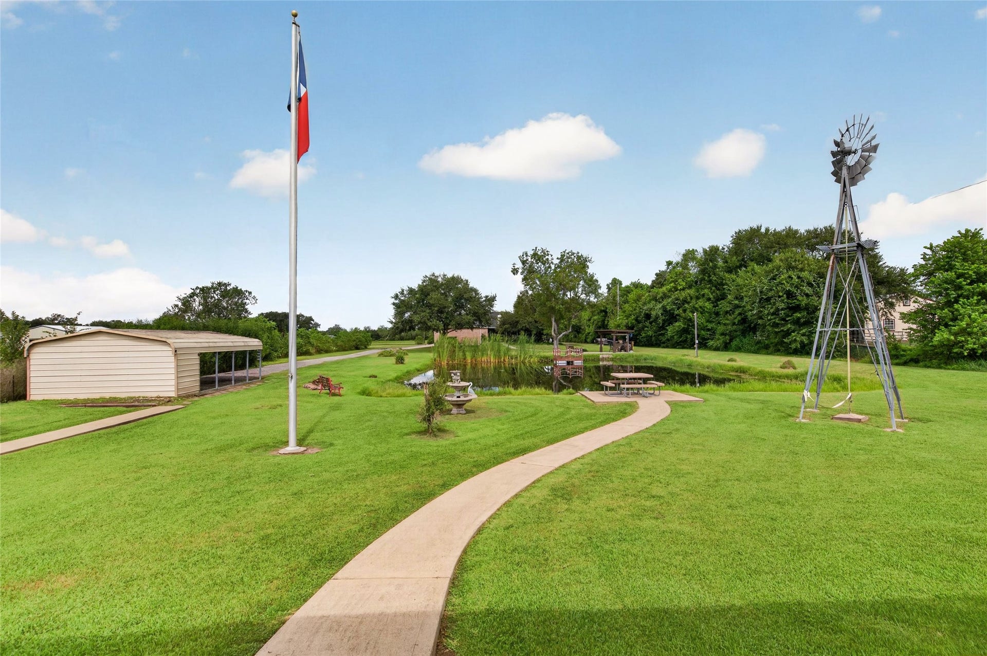 4933 1/2 Powers Ln, Alvin, TX 77511 Spacious covered parking area with a gravel drive and attached storage building.