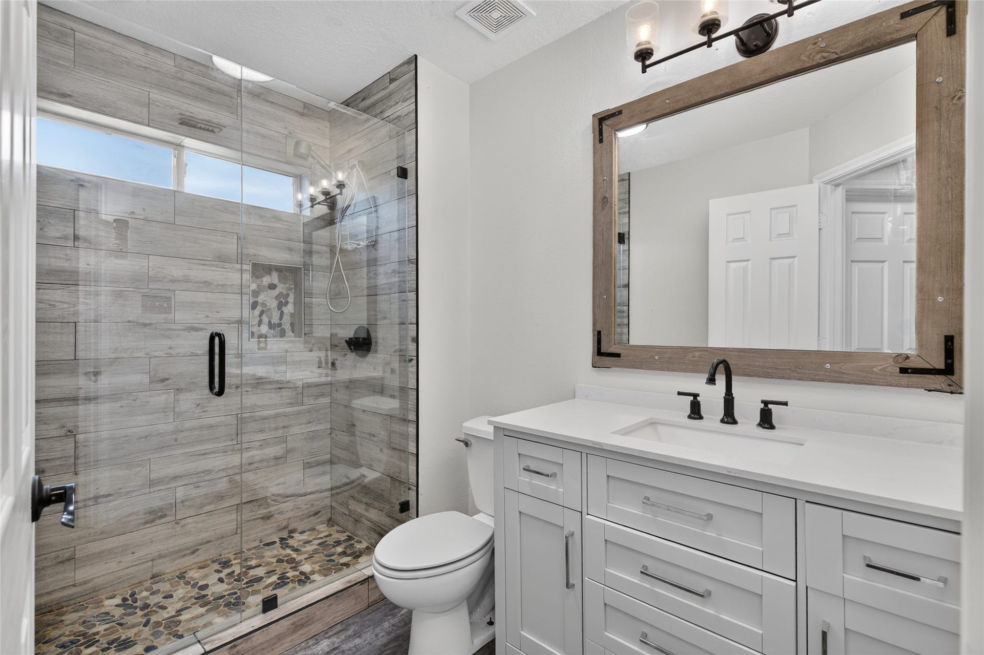 4933 1/2 Powers Ln, Alvin, TX 77511 Guest bath with an updated custom shower, tile surround, frameless glass door, and modern vanity.