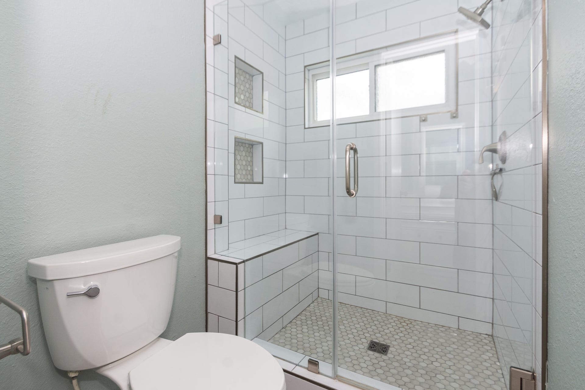 4509 Country Club Drive, Dickinson, TX 77539 Primary Bathroom Glass-enclosed stand-up shower with a built-in bench, dual recessed niches, and fresh subway tile.