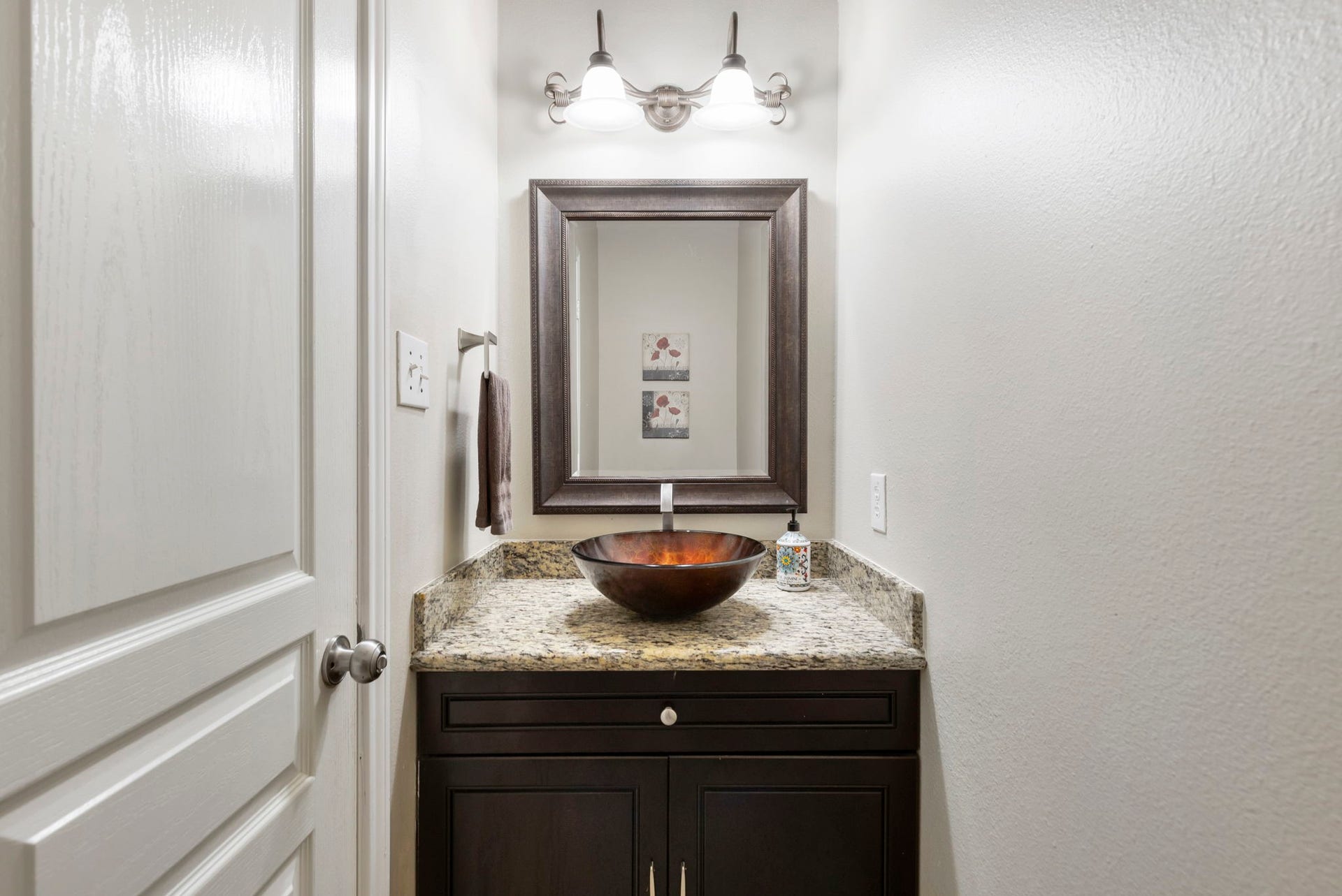 14 N Bardsbrook Circle, The Woodlands, TX 77382 The conveniently located first-floor half bathroom features granite countertops and a stylish vessel sink, perfect for guests.