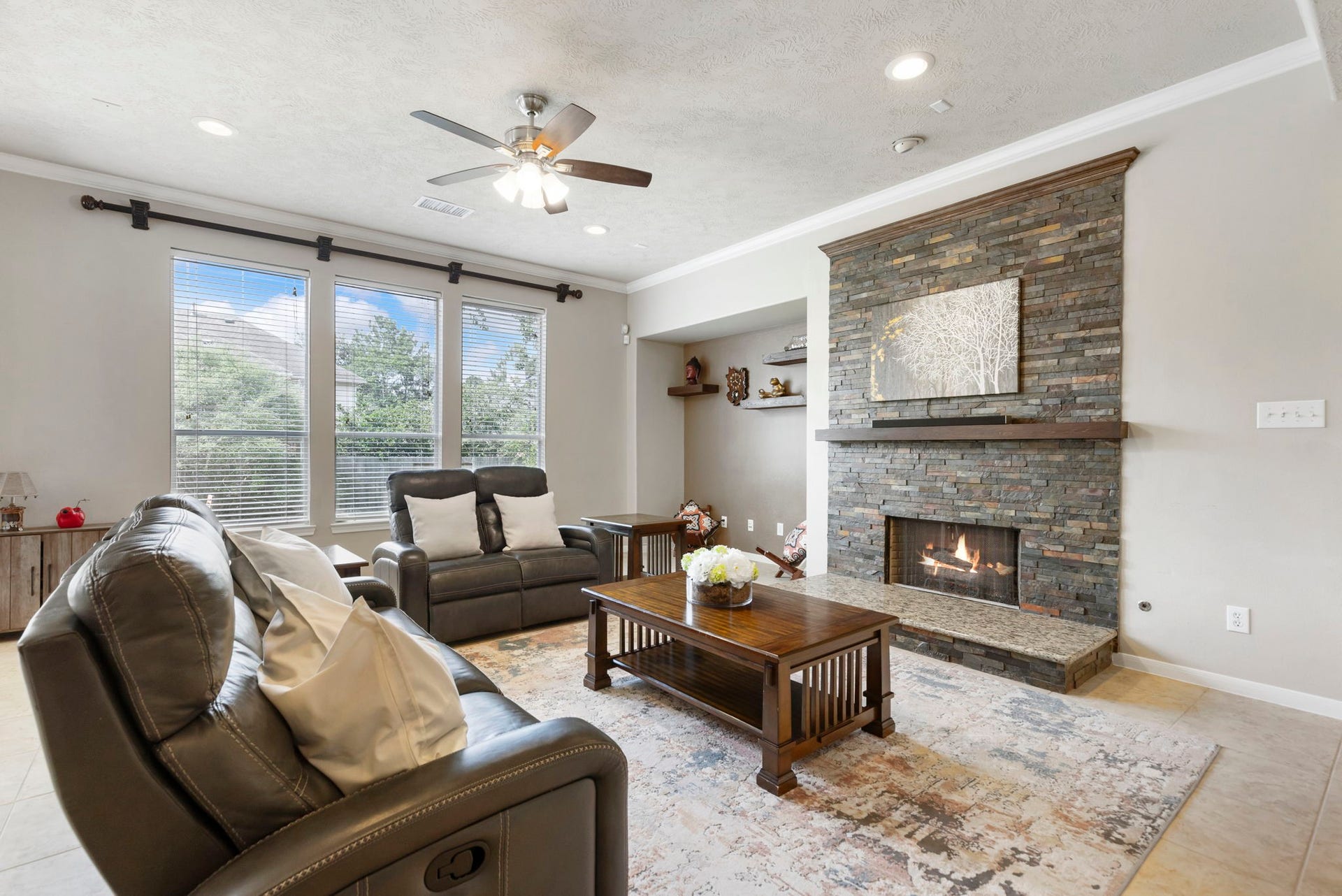 14 N Bardsbrook Circle, The Woodlands, TX 77382 The inviting living room features large windows, a beautiful floor-to-ceiling stone fireplace, and plenty of space to gather and unwind.