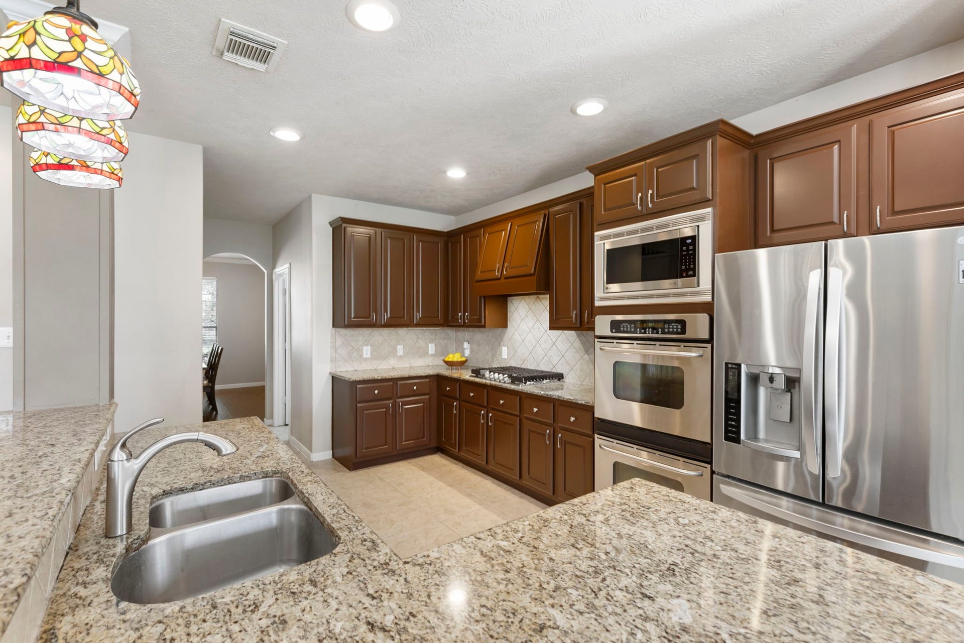 14 N Bardsbrook Circle, The Woodlands, TX 77382 The spacious island kitchen features granite countertops, stainless steel appliances, double ovens, and abundant cabinetry for both storage and functionality.