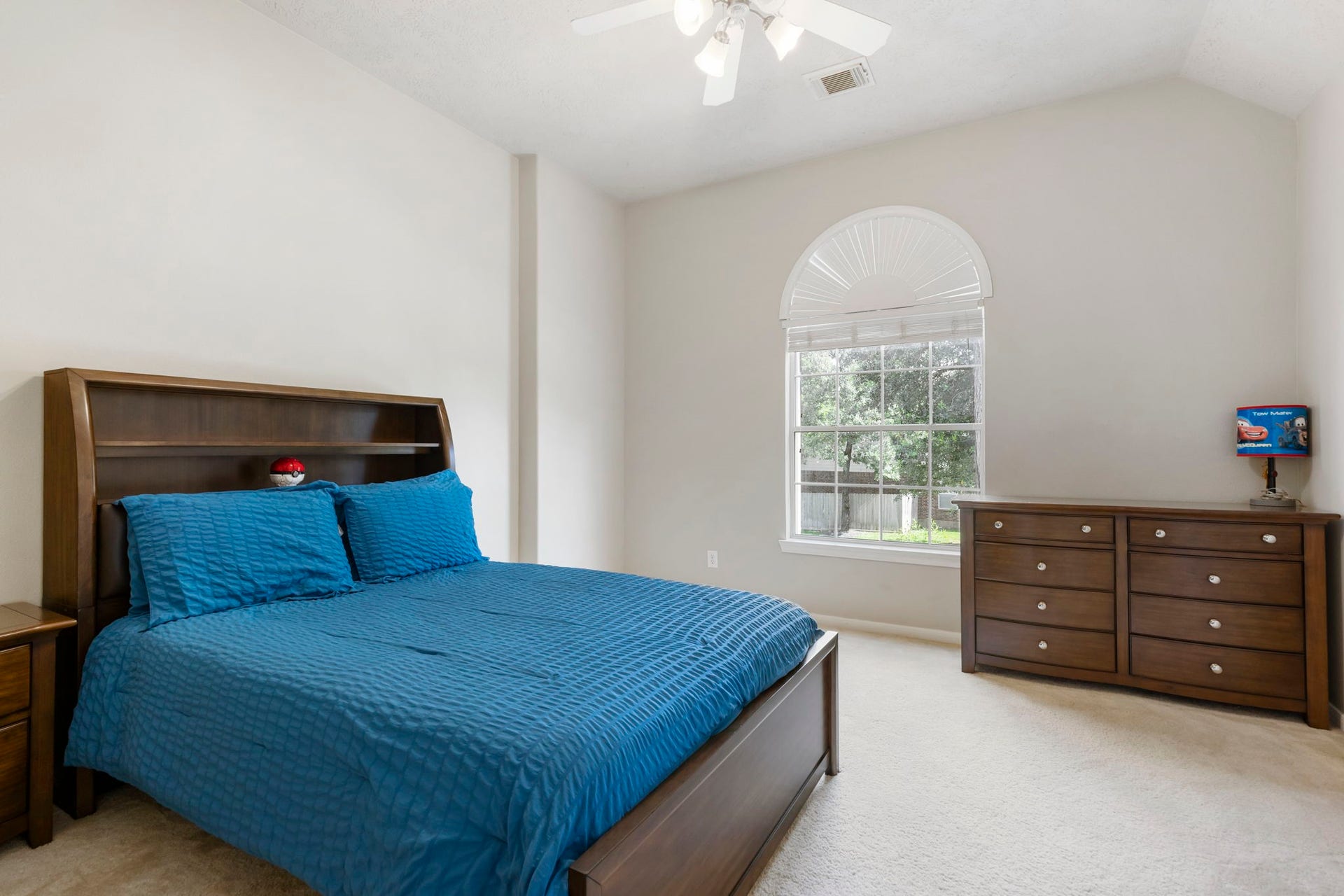 14 N Bardsbrook Circle, The Woodlands, TX 77382 This bright secondary bedroom showcases a beautiful arched window, elevated ceilings, and a ceiling fan while still offering plenty of room for furniture and personalization.