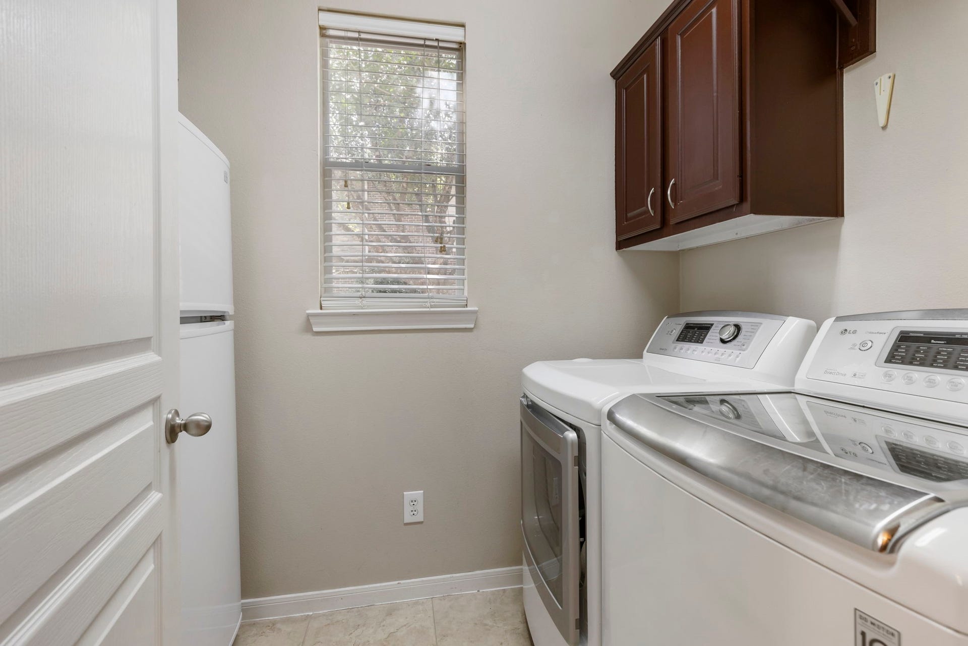14 N Bardsbrook Circle, The Woodlands, TX 77382 A in house laundry room with built-in cabinetry provides extra storage and convenience to help keep everyday tasks organized.