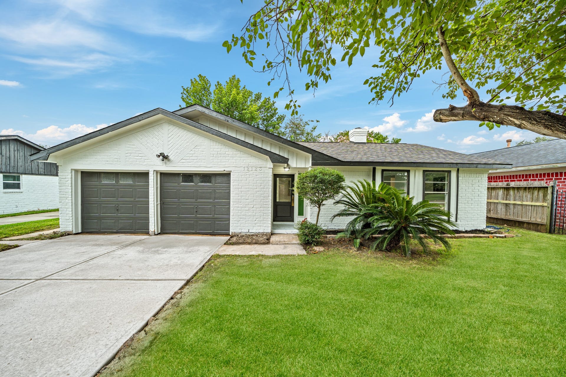 12123 Pompano Lane, Houston, TX 77072 Charming single-story home with a classic white brick exterior, featuring a double garage and a well-maintained front yard surrounded by mature trees.