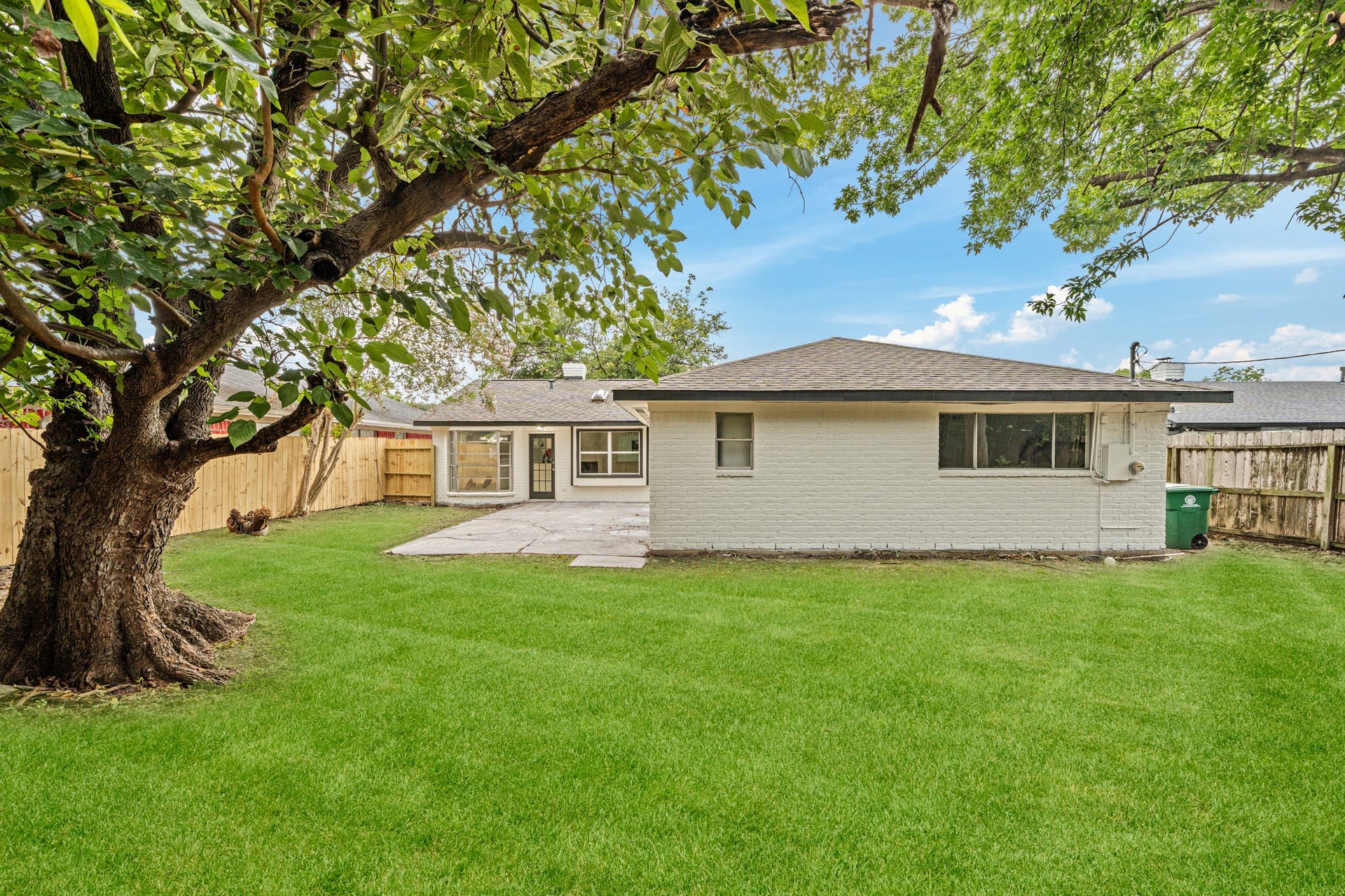 12123 Pompano Lane, Houston, TX 77072 Charming backyard with a spacious lawn, mature tree, and a cozy patio area, perfect for outdoor gatherings.