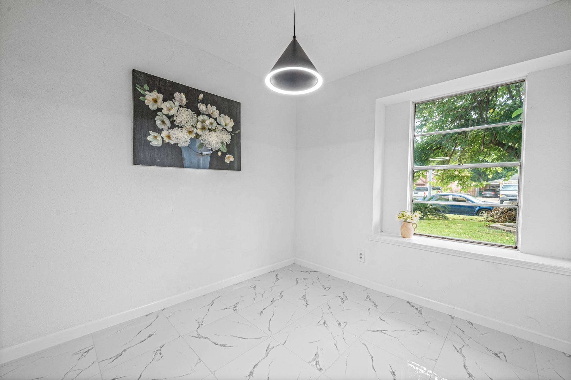 12123 Pompano Lane, Houston, TX 77072 Bright and airy room with white marble flooring, a modern pendant light, and a large window offering plenty of natural light.