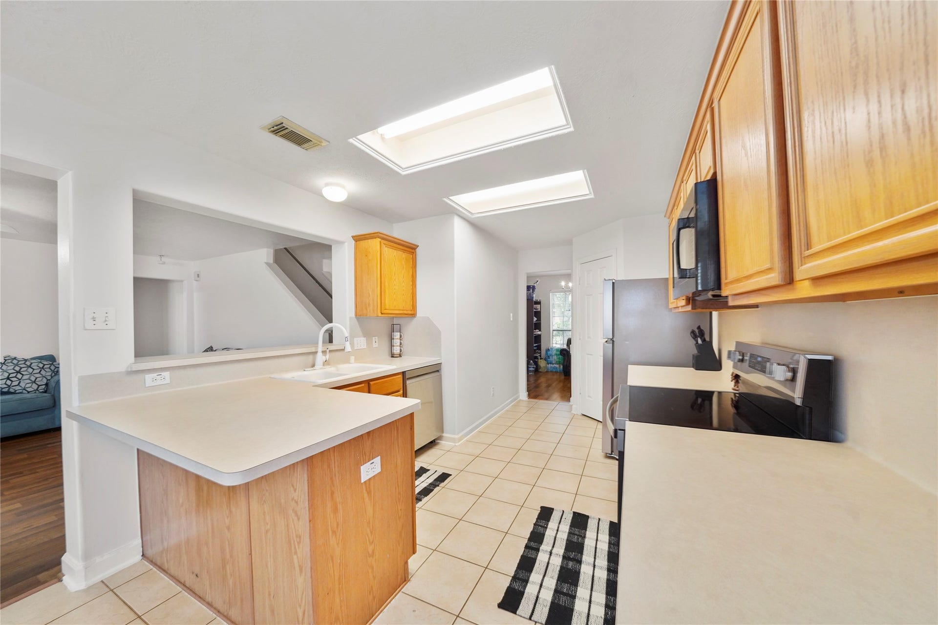 5614 Gaffney Lane, Houston, TX 77084 Warm cabinetry, a broad serving peninsula, and open sightlines make the kitchen practical and inviting; the range, over-the-range microwave, stainless steel refrigerator and dishwasher were replaced in August 2026.