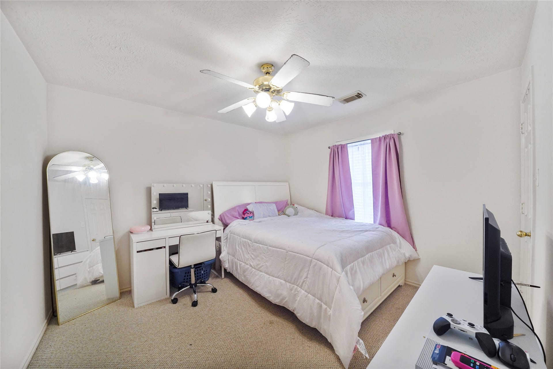 5614 Gaffney Lane, Houston, TX 77084 Another secondary bedroom offers a comfortable setup for guests, hobbies, or a home office, with soft carpet and a cheerful window.