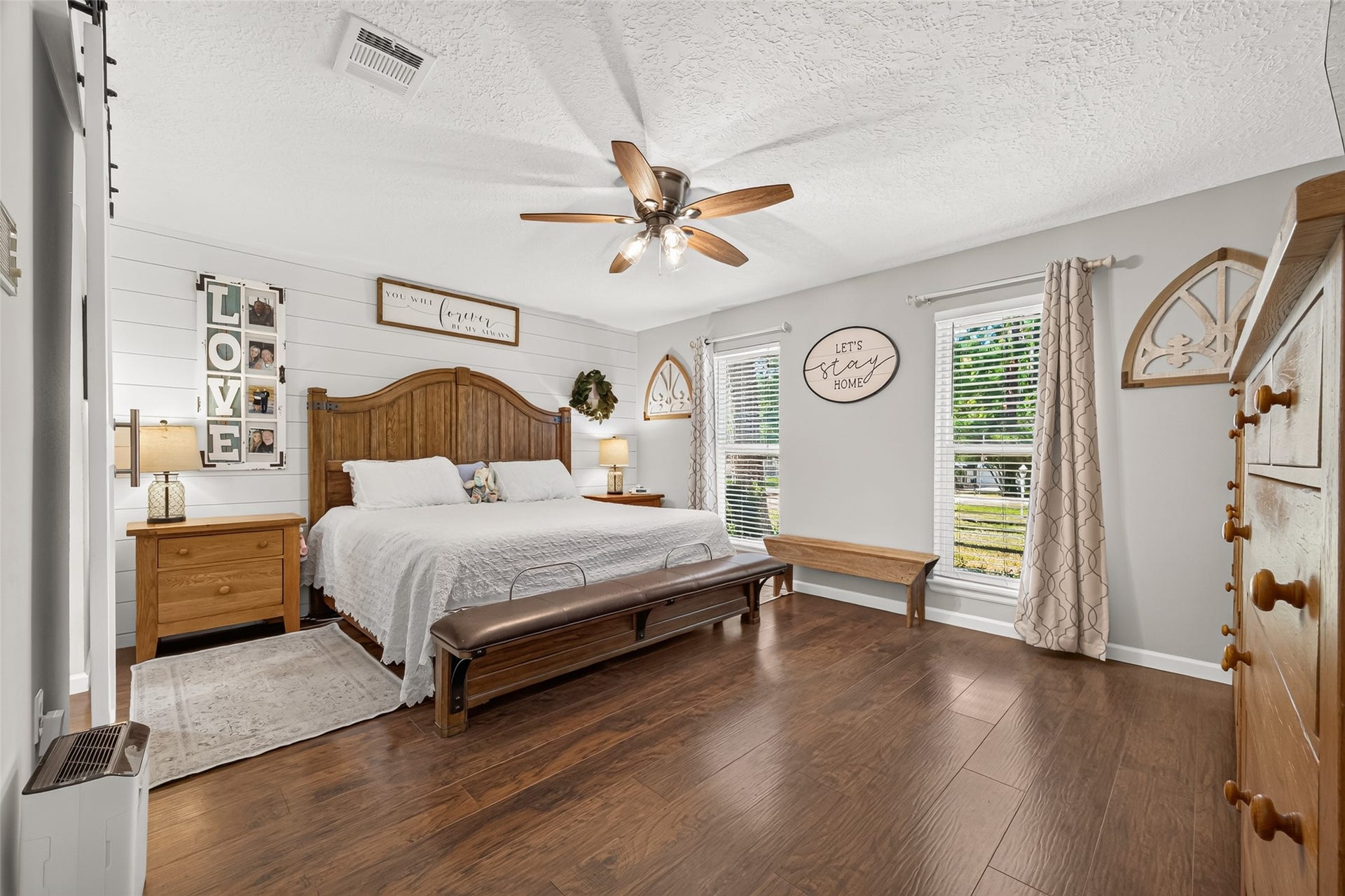 1535 Memorial Drive, Conroe, TX 77304 LOOK AT THIS SPACIOUS PRIMARY BEDROOM WITH THE ADDED SHIPLAP ACCENT WALL, BEAUTIFUL WOOD LIKE TILE FLOORS, LOTS OF NATURAL LIGHT; CURTAIN AND CURTAIN ROD WILL REMAIN WITH HOME