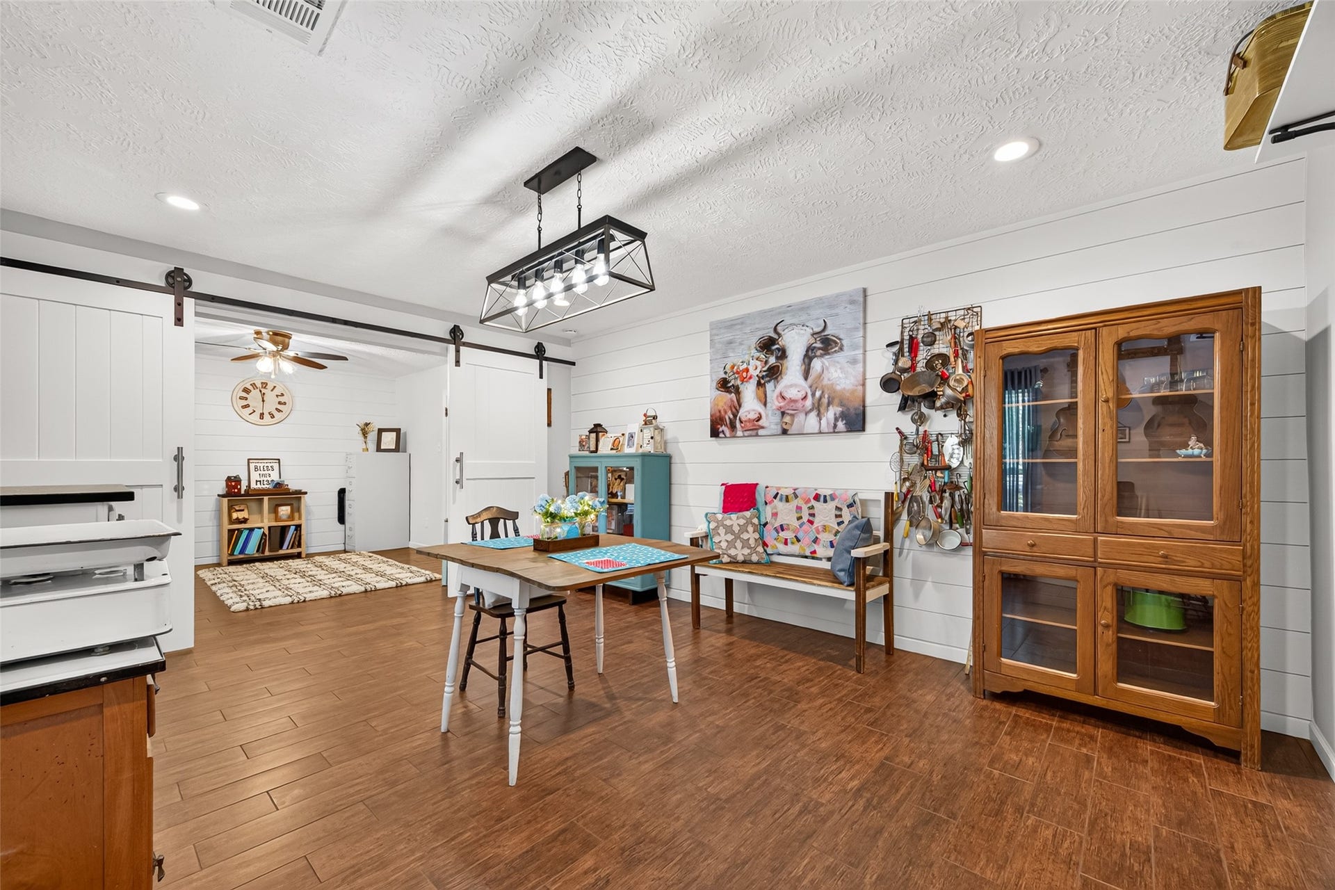 1535 Memorial Drive, Conroe, TX 77304 LOOK AT THE BEAUTIFUL WOOD LIKE TILE FLOORS (GROUT HAS BEEN RECENTLY RESEALED); THIS IS THE FORMAL DINING ROOM FOR ENJOYING YOUR FAMILY DURING SPECIAL GATHERINGS; ADDED SHIPLAP ACCENT WALL; ADDED A FARMHOUSE LIGHT FIXTURE; ADDED THE SLIDING DOUBLE BARN DOORS BETWEEN THE DINING ROOM AND THE OFFICE; THE DOUBLE BARNS HANDLES MATCHES THE REST OF THE CABINETS IN THE HOME.