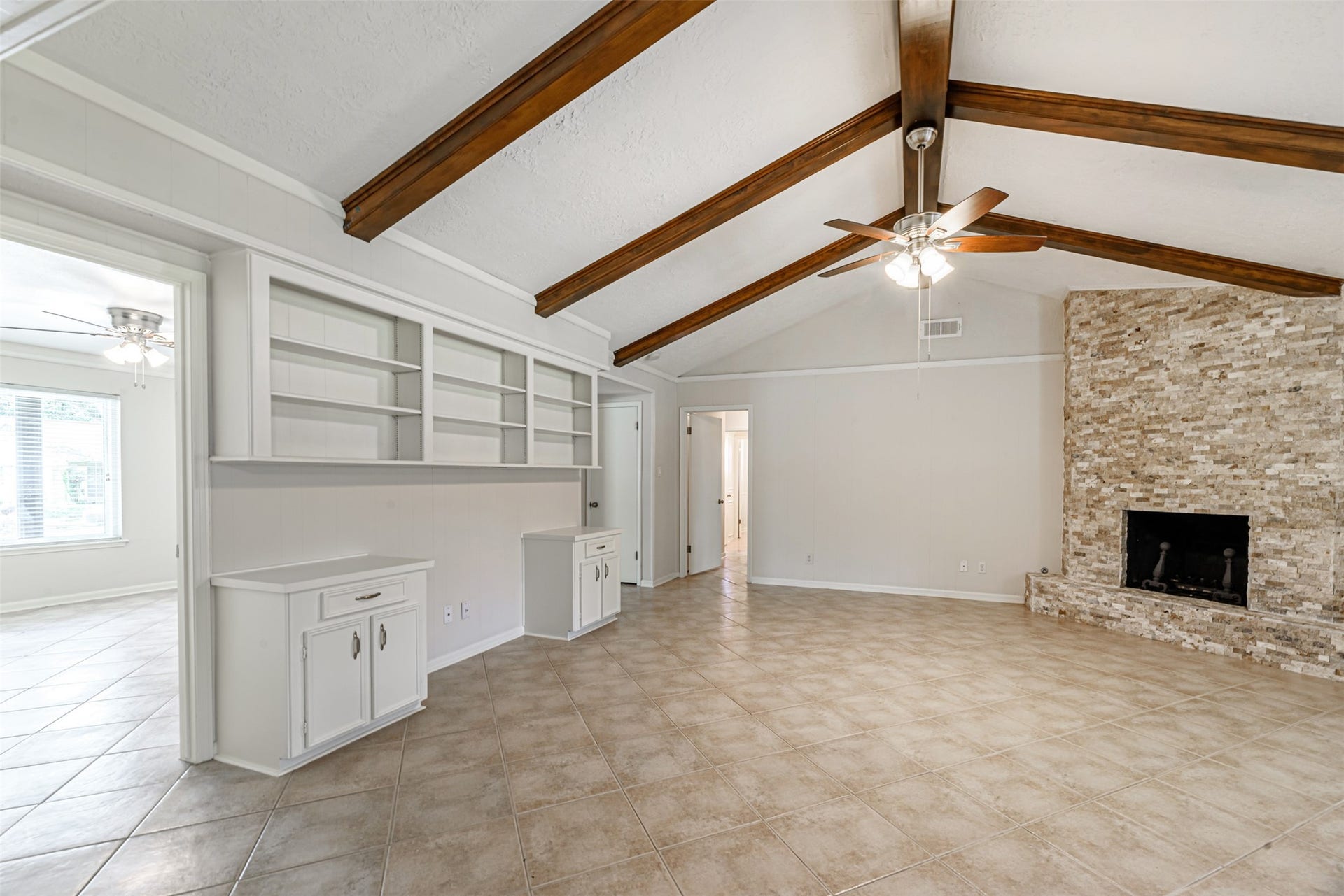 124 Dogwood Street, Sugar Land, TX 77478 Step into the inviting formal living room through the access door on the left, featuring elegant wood-beamed ceilings, a cozy stone fireplace, and built-in shelving for a touch of sophistication.