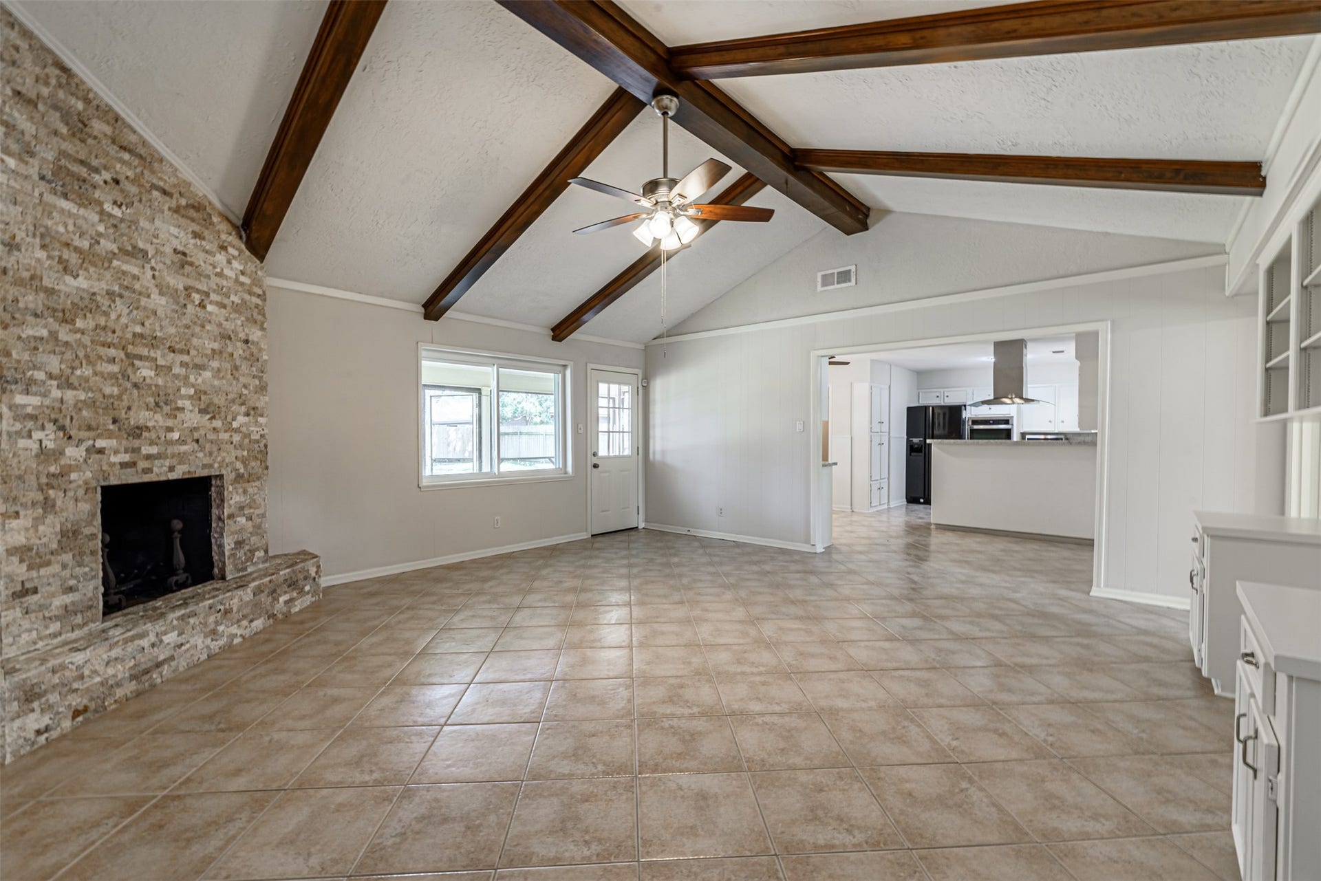 124 Dogwood Street, Sugar Land, TX 77478 The expansive family room with its elegant beamed ceiling seamlessly flows into a modern kitchen, creating a perfect space for family gatherings.