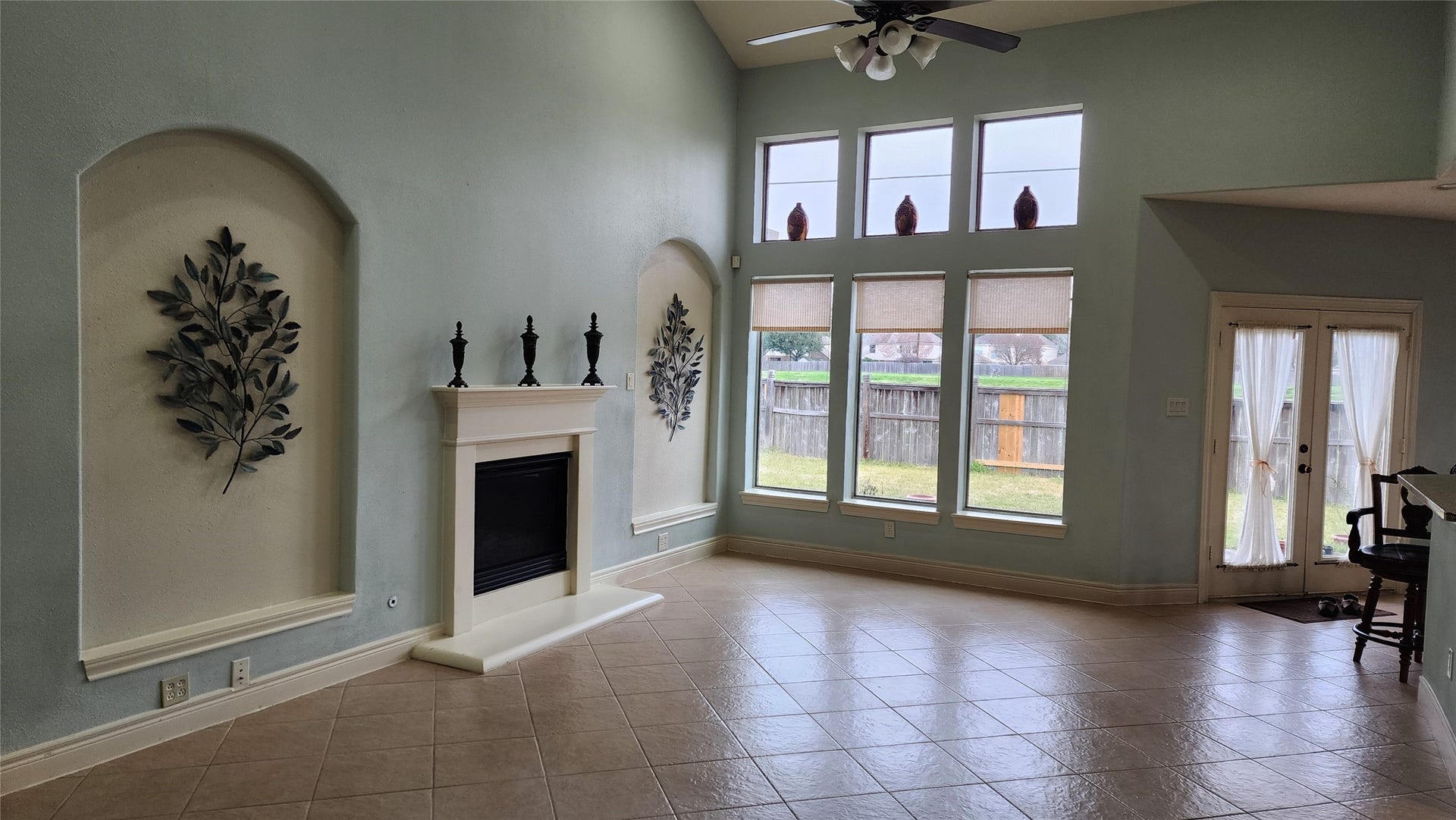 5442 Faircreek Ln Lane, Katy, TX 77450 Spacious living room with soaring ceilings, a cozy fireplace, elegant wall niches, and abundant natural light pouring through tall windows, creating an inviting atmosphere perfect for relaxation and entertaining.