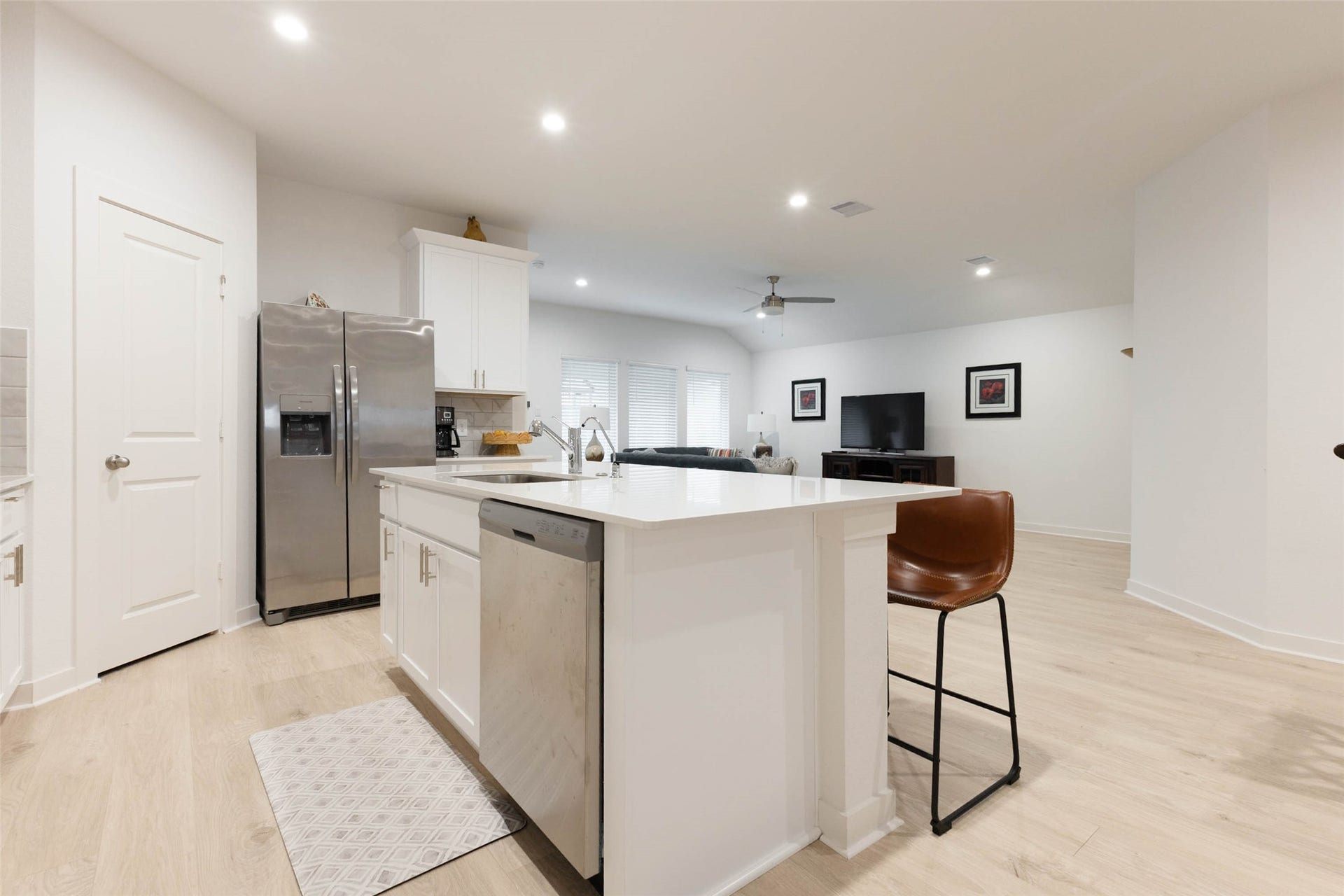 30502 White Cliff Court, Fulshear, TX 77441 Modern open-concept kitchen and living area featuring a spacious island with seating, stainless steel appliances, and sleek light wood flooring.