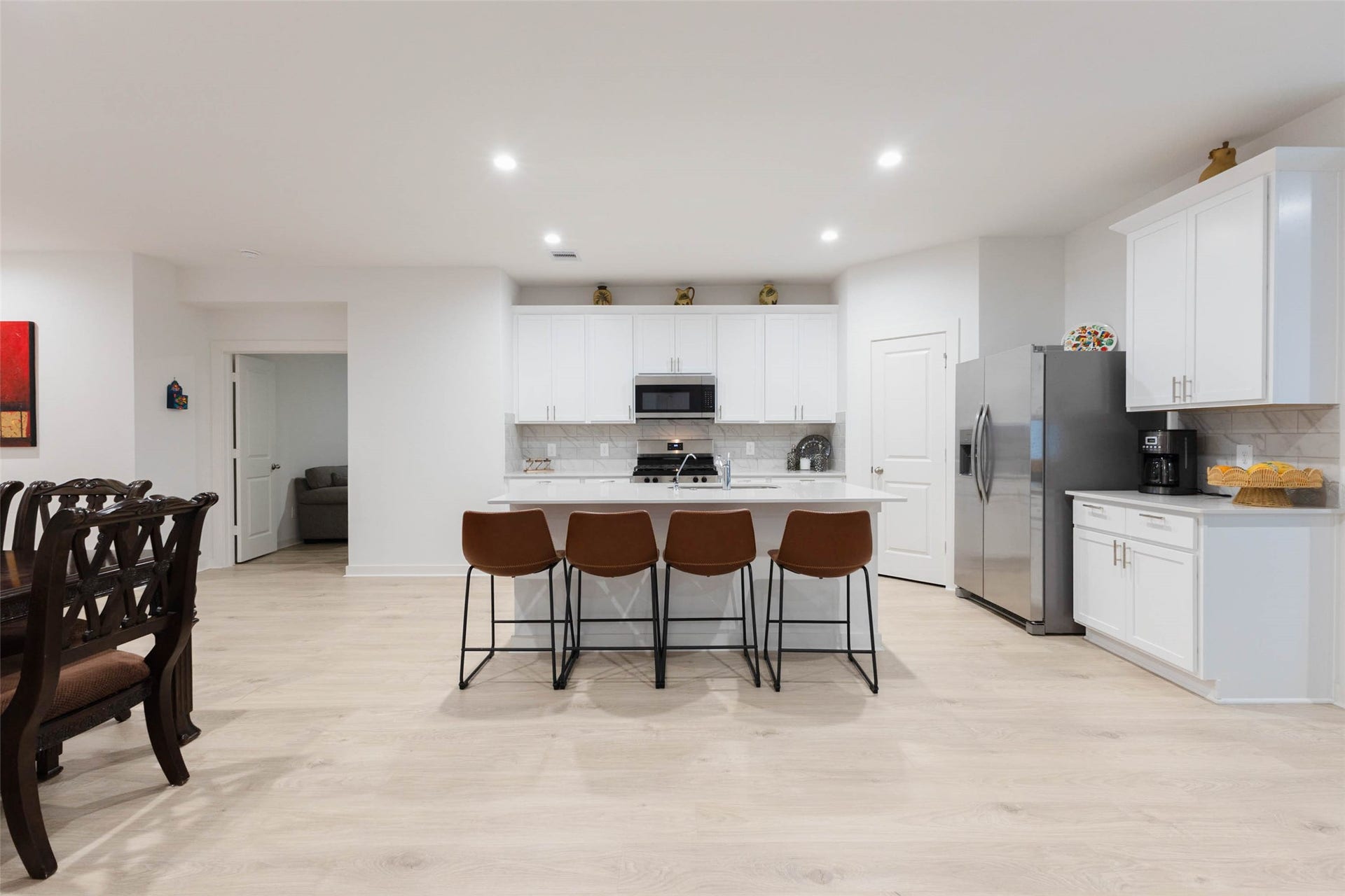 30502 White Cliff Court, Fulshear, TX 77441 Experience modern elegance in this expansive kitchen featuring sleek white cabinetry, a large island with seating, stainless steel appliances, and stylish lighting. Perfect for culinary adventures and entertaining.