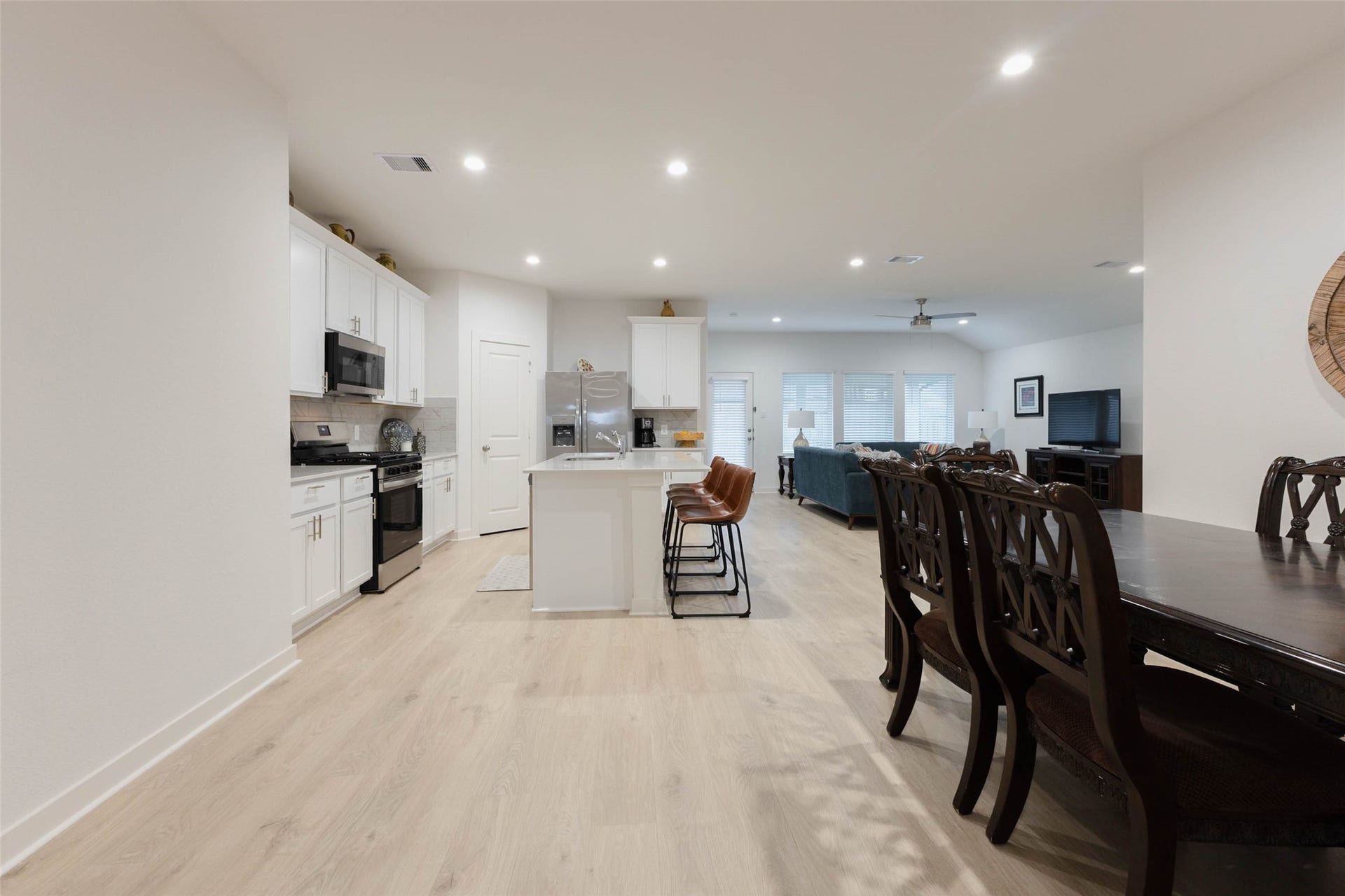 30502 White Cliff Court, Fulshear, TX 77441 Bright and spacious open-concept living area featuring a modern kitchen with white cabinetry, a central island with seating, and a cozy living room, perfect for entertaining.