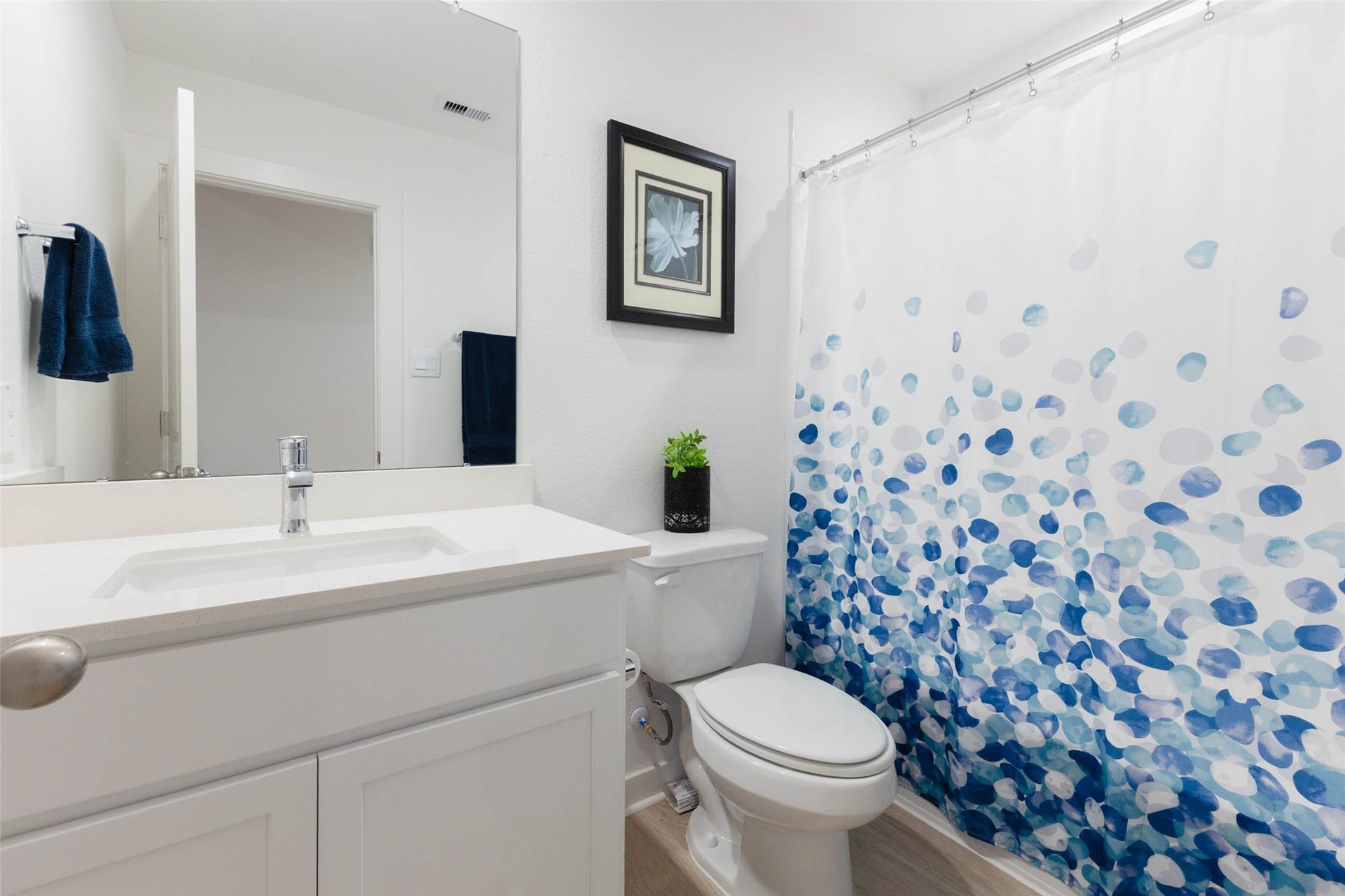 30502 White Cliff Court, Fulshear, TX 77441 Bright and modern bathroom featuring sleek white cabinetry, a stylish blue-patterned shower curtain, and tasteful decor.