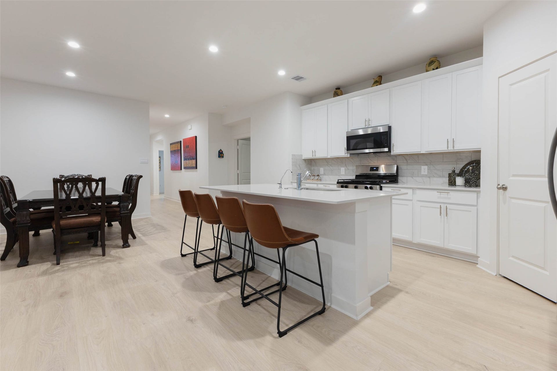 30502 White Cliff Court, Fulshear, TX 77441 Sleek, modern kitchen with white cabinetry, stainless steel appliances, and a spacious island, seamlessly flowing into a cozy dining area.
