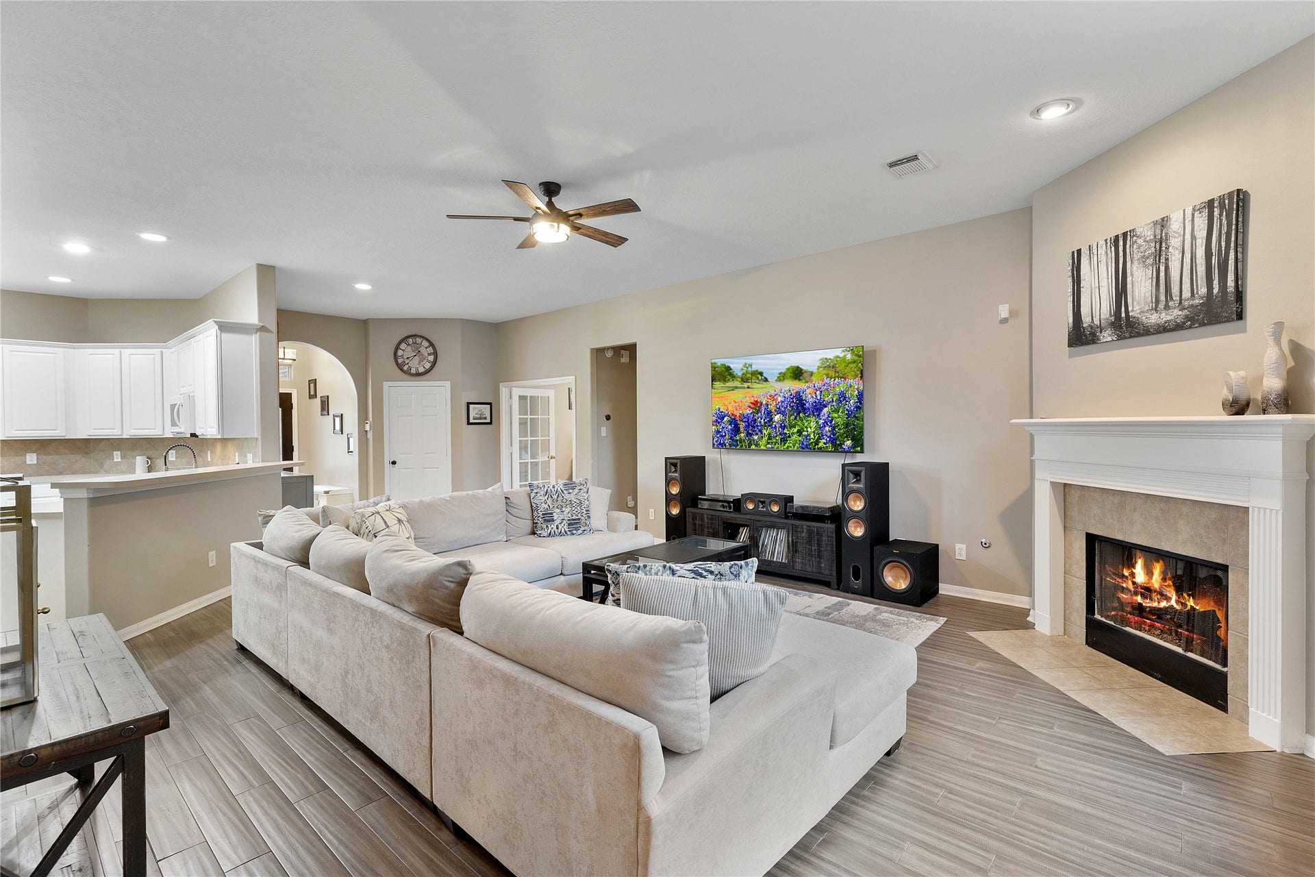 18343 Otter Creek Trail, Humble, TX 77346 Spacious living room with a cozy fireplace, modern flooring, and an elegant, open layout leading to a bright kitchen. Perfect for entertaining.
