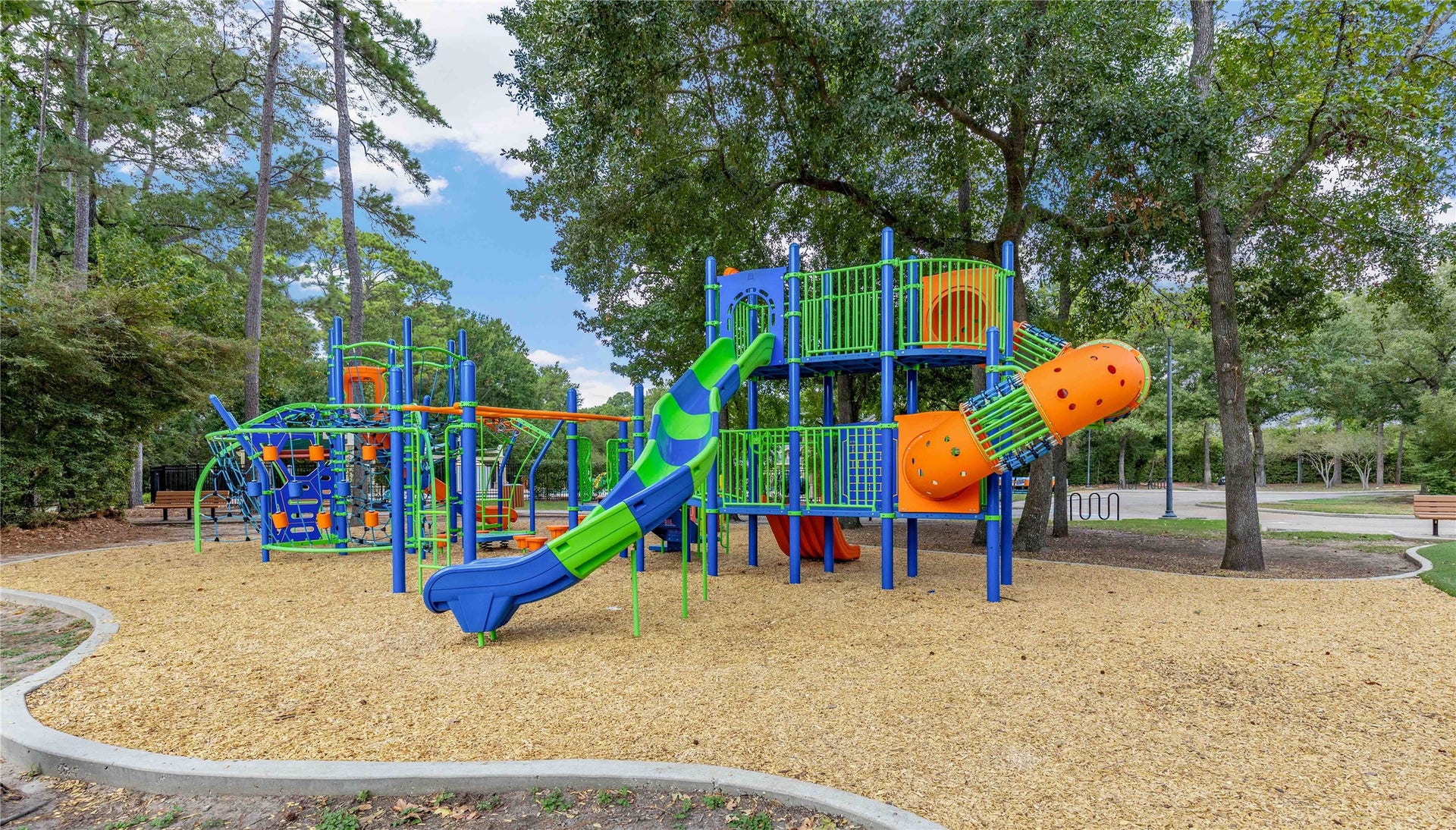 18343 Otter Creek Trail, Humble, TX 77346 Discover vibrant community amenities featuring a colorful playground nestled among lush trees, offering endless fun for families in a serene setting.