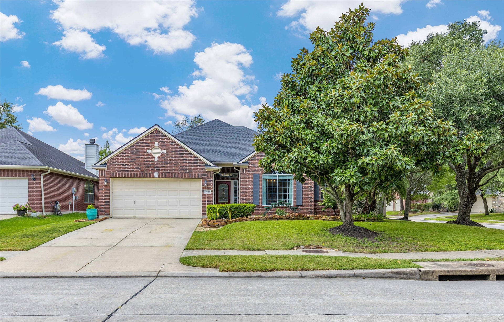 18343 Otter Creek Trail, Humble, TX 77346 Charming brick home with a spacious two-car garage and beautifully manicured front yard, featuring a mature magnolia tree and inviting curb appeal.