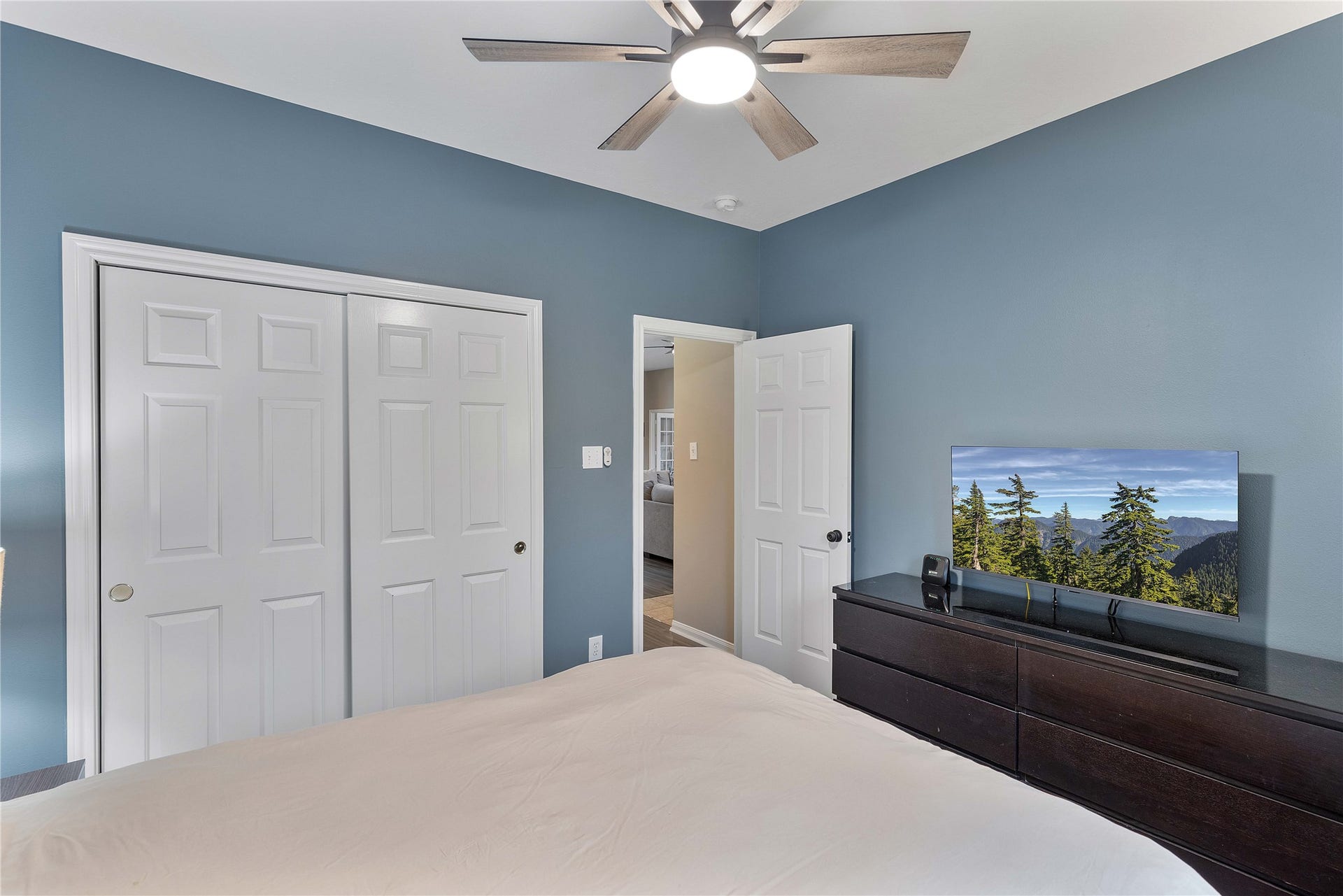 18343 Otter Creek Trail, Humble, TX 77346 Cozy bedroom featuring soothing blue walls, a modern ceiling fan ,and ample closet space with sliding doors.