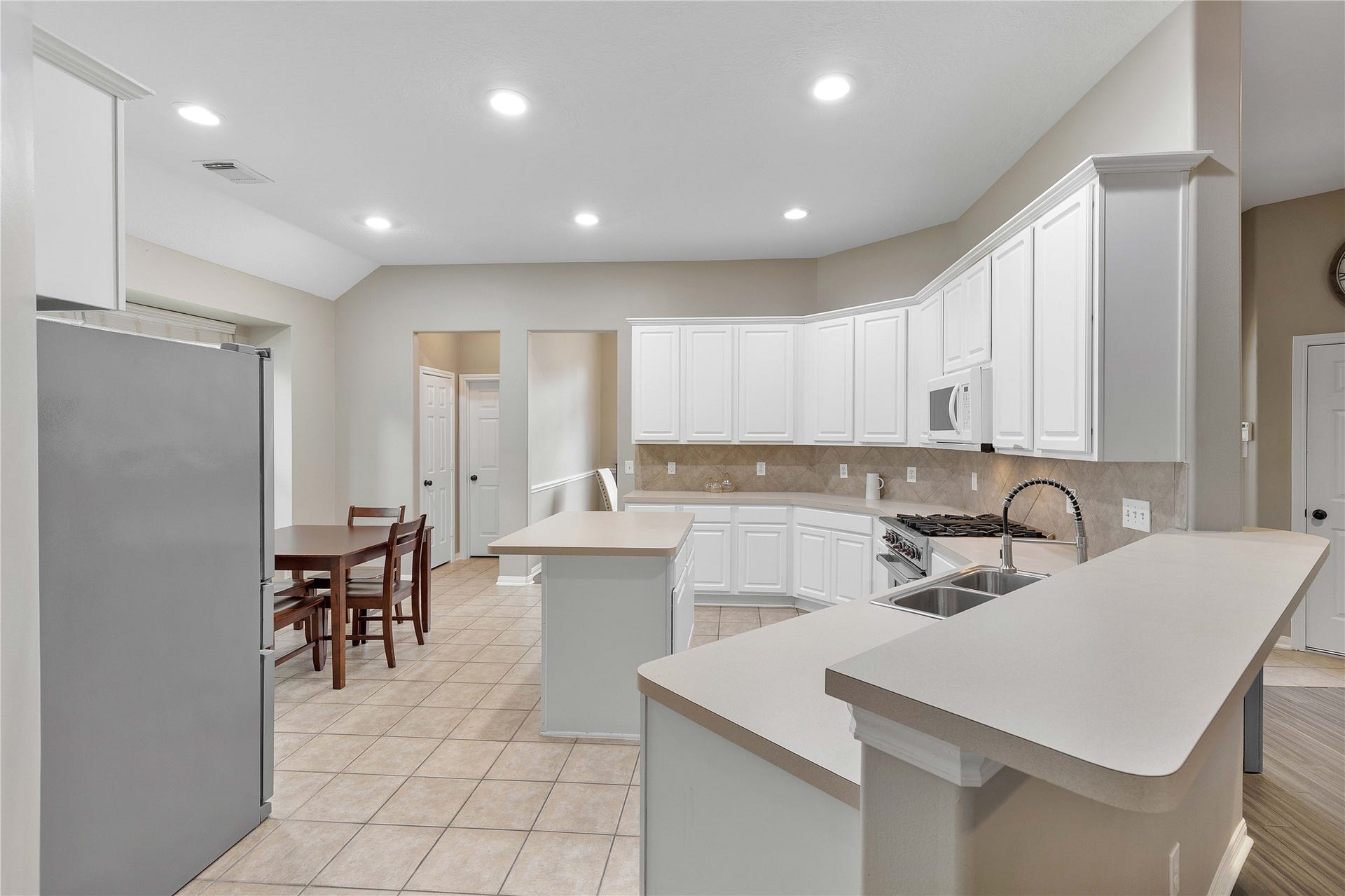 18343 Otter Creek Trail, Humble, TX 77346 Spacious kitchen with sleek white cabinetry, modern appliances, and ample counter space, perfect for entertaining and family meals.