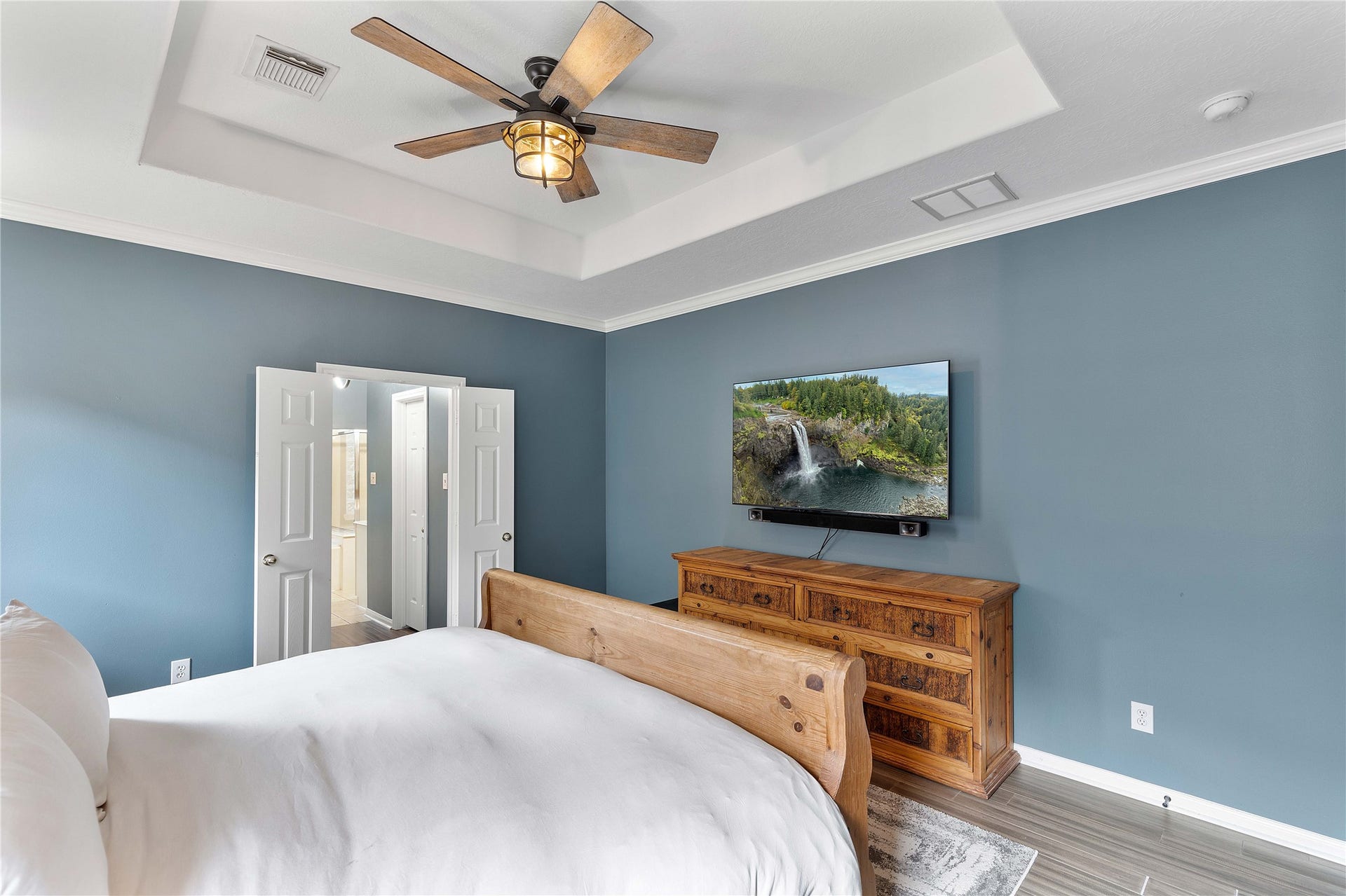 18343 Otter Creek Trail, Humble, TX 77346 Spacious bedroom featuring a stylish tray ceiling, modern ceiling fan, and soothing blue walls.