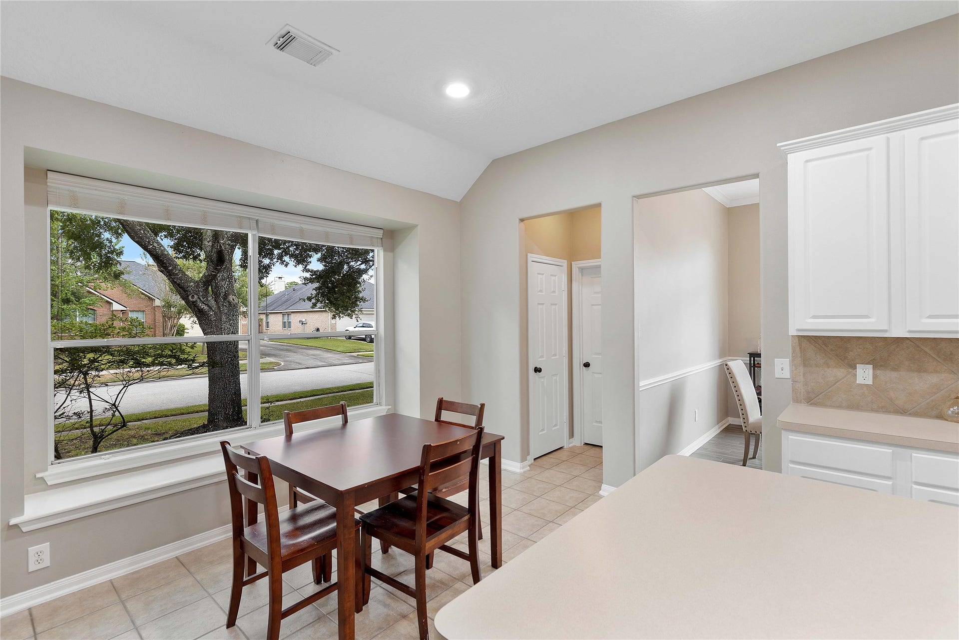18343 Otter Creek Trail, Humble, TX 77346 Bright dining area with large window views, tile flooring, and access to a cozy kitchen with white cabinetry.