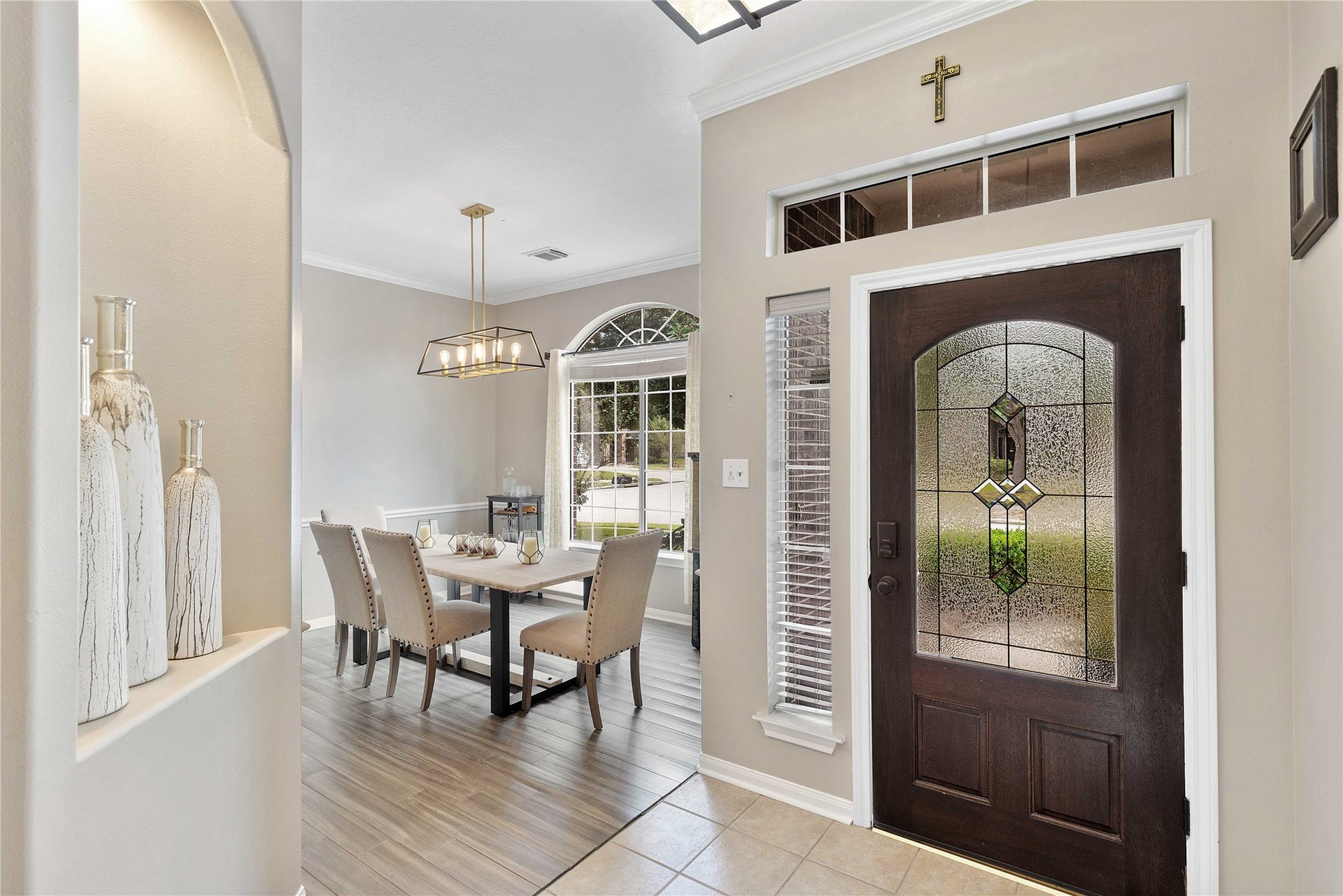 18343 Otter Creek Trail, Humble, TX 77346 An elegant entryway with a stunning glass front door leads to a bright dining area featuring modern lighting and a large window.