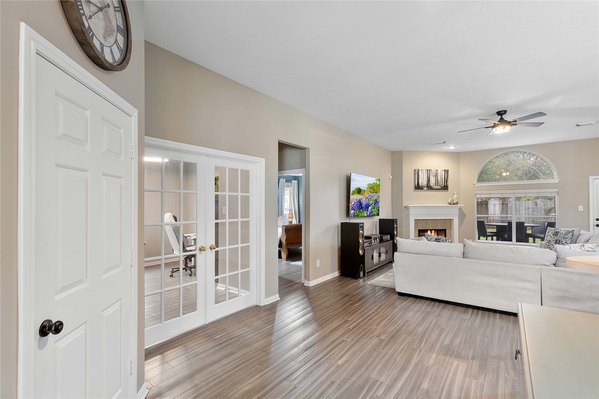 18343 Otter Creek Trail, Humble, TX 77346 Spacious living area featuring elegant flooring, a cozy fireplace, and abundant natural light from large windows. Adjacent is a stylish office space with French doors, perfect for work-from-home convenience.