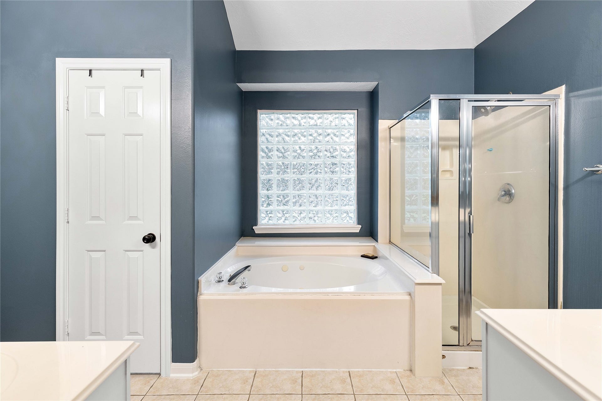 18343 Otter Creek Trail, Humble, TX 77346 Elegant bathroom featuring a spacious soaking tub, separate glass-enclosed shower, and stylish blue-gray walls for a serene ambiance.