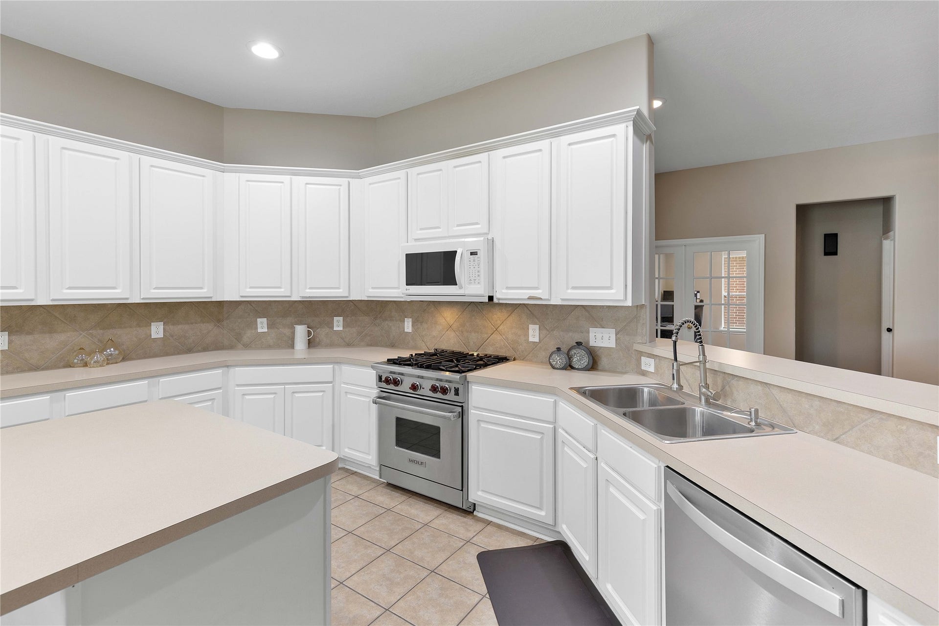 18343 Otter Creek Trail, Humble, TX 77346 Spacious kitchen with sleek white cabinetry, modern appliances, and a convenient breakfast bar, perfect for culinary enthusiasts.