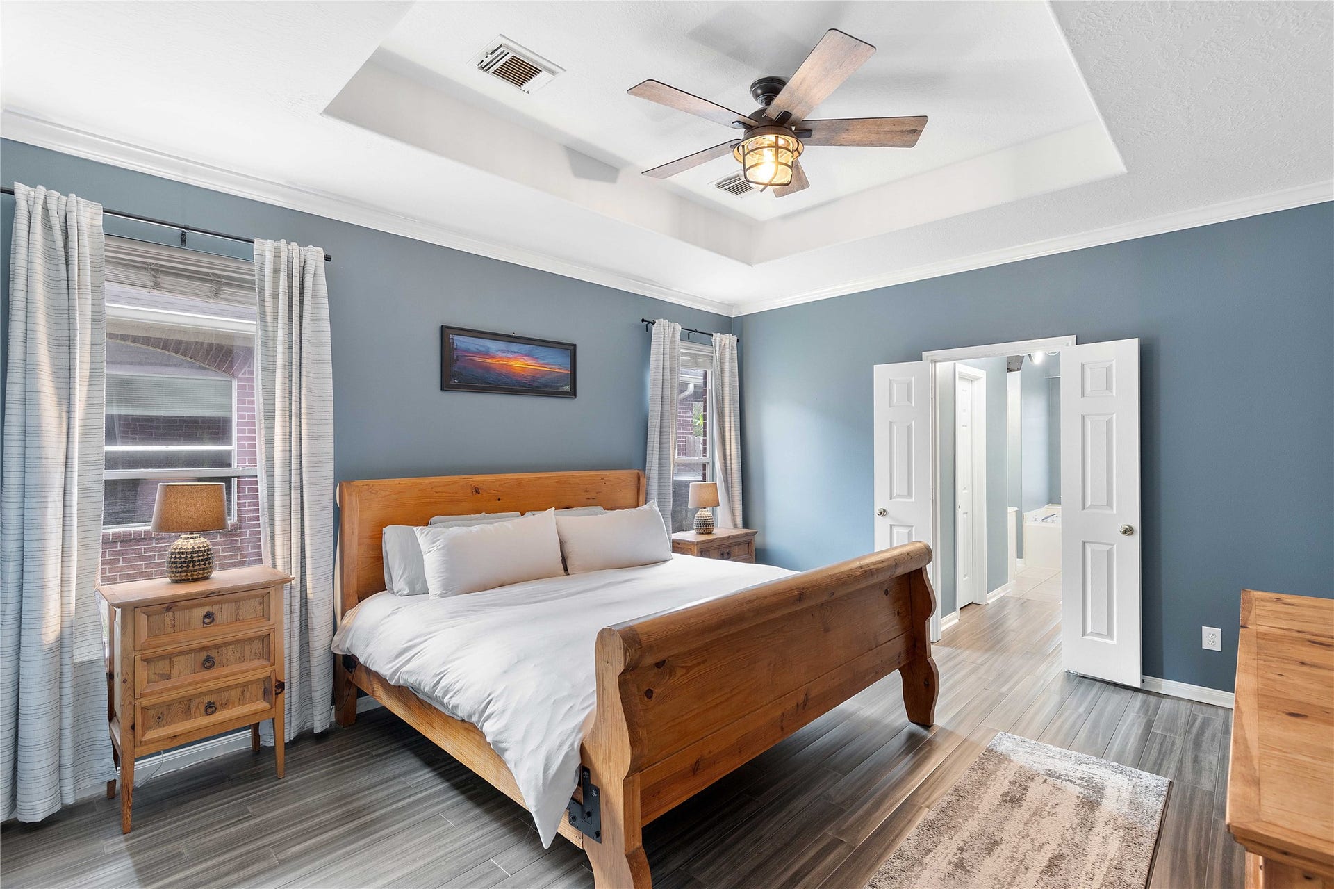 18343 Otter Creek Trail, Humble, TX 77346 Experience ultimate comfort in this inviting primary bedroom featuring a stylish tray ceiling, sleek flooring, and abundant natural light, offering a serene retreat.