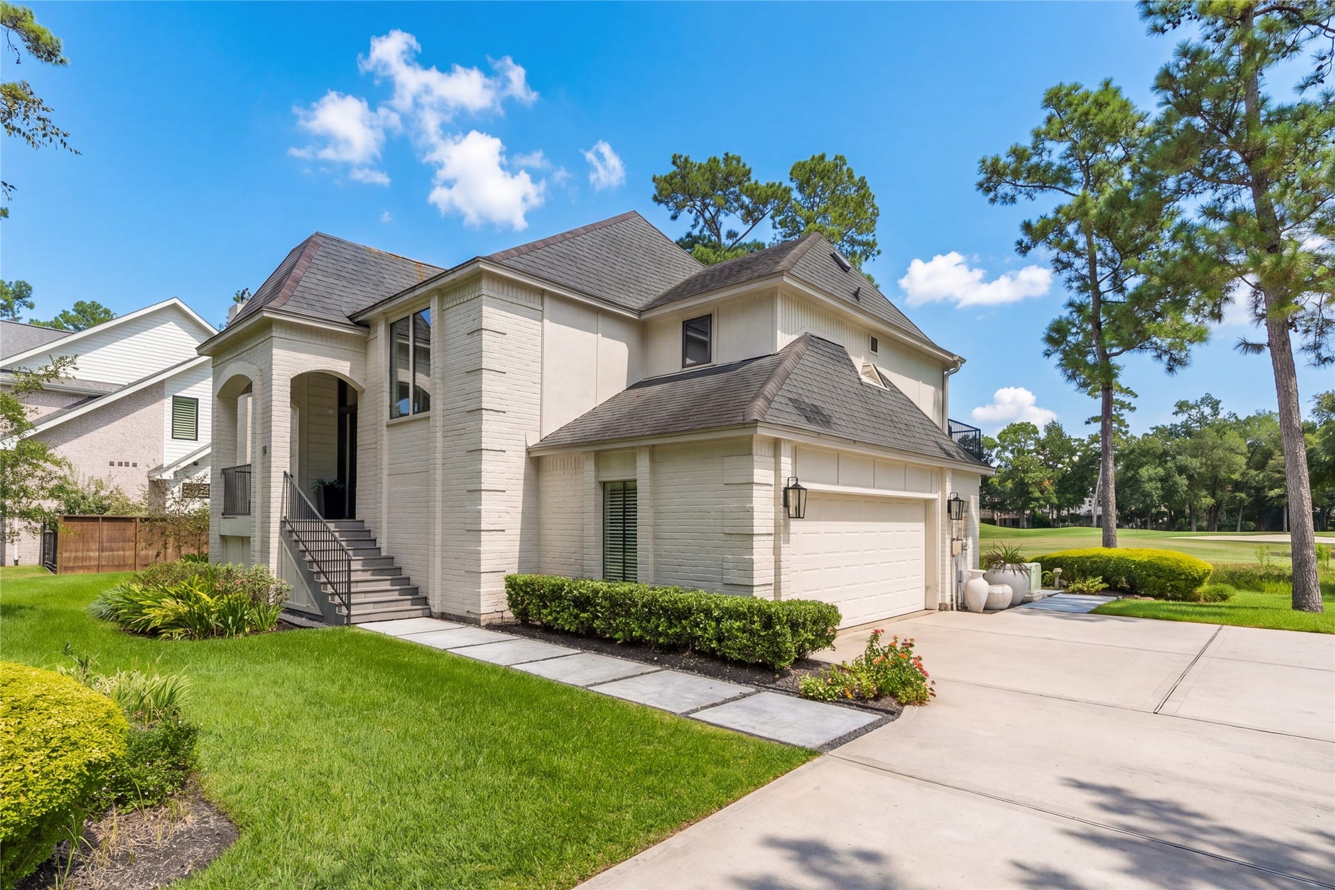 75 Huntsmans Horn Circle, The Woodlands, TX 77380 Elegant two-story home with a modern brick facade, manicured landscaping, and a spacious driveway leading to a two-car garage, nestled in a peaceful neighborhood setting.