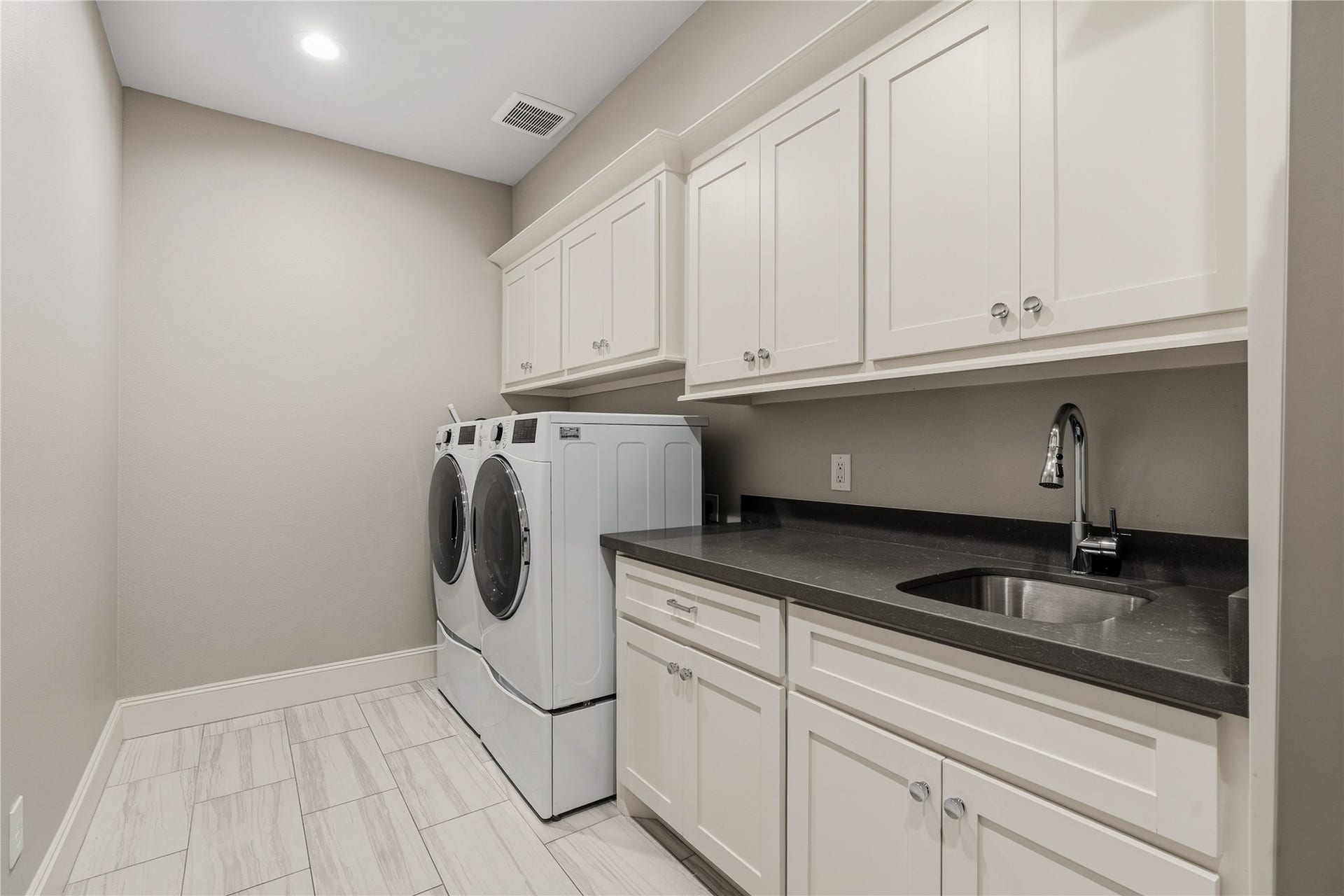 75 Huntsmans Horn Circle, The Woodlands, TX 77380 Spacious laundry room featuring sleek cabinetry, a modern washer and dryer, and a convenient utility sink with ample countertop space for all your laundry needs.
