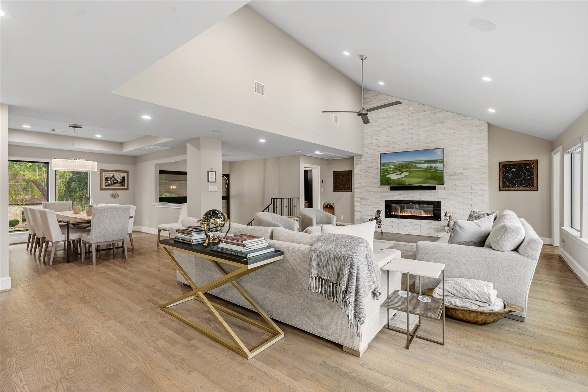 75 Huntsmans Horn Circle, The Woodlands, TX 77380 Spacious open-concept living area with a vaulted ceiling, featuring a cozy fireplace and modern finishes, seamlessly connected to a stylish dining space with large windows for natural light.